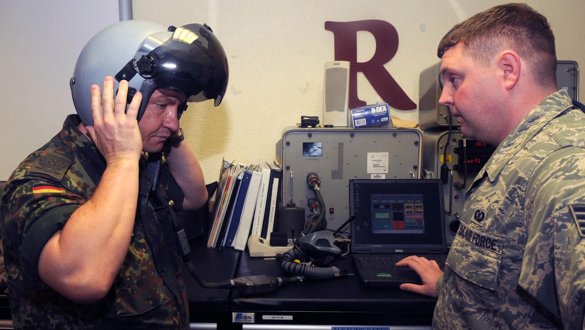 SPANGDAHLEM AIR BASE, Germany – Lt. Col. Dietmar KÖppen, German air force pilot, tries on a helmet as Staff Sgt. Jason Clark, 52nd Operations Support Squadron demonstrates how it works Sept. 23.  Colonel KÖppen was here participating in the Vienna Document 1999 Evaluation exercise, an ongoing inspection program designed to ensure the base is ready for treaty compliance inspections and evaluations.  (U.S. Air Force photo/Staff Sgt. Logan Tuttle)