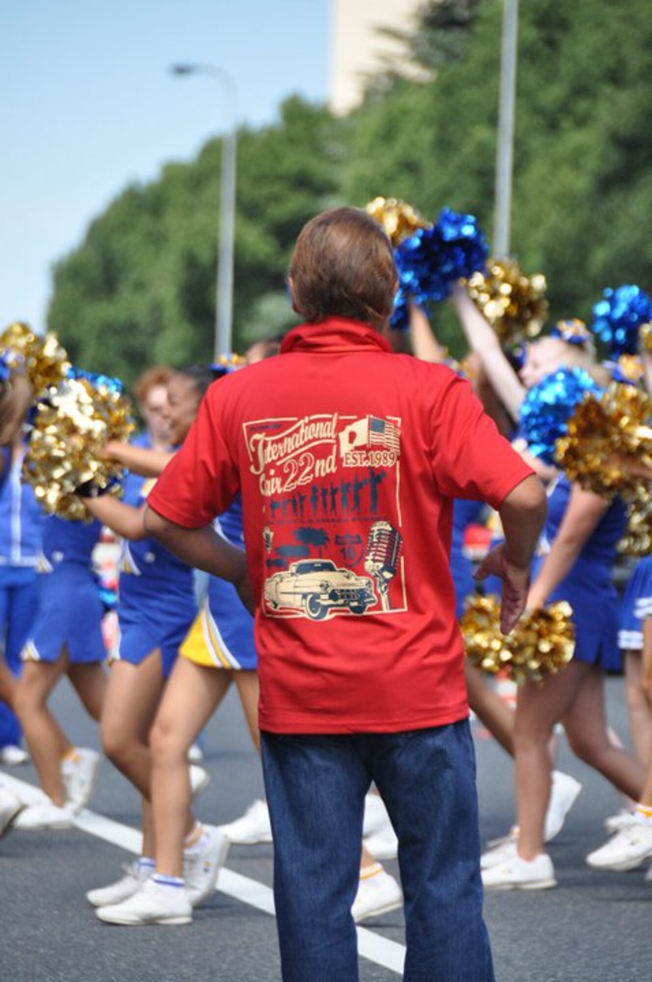YOKOTA AIR BASE, Japan - The Yokota High School Cheerleaders perform for the reviewing stand, while a parade coordinator looks on.  The parade, which was held as part of the 2010 Fussa International Fair featured Japanese school bands, vehicles from the 374th Airlift Wing, as well as classic cars.  (U.S. Air Force photo/Capt. Tania Bryan)