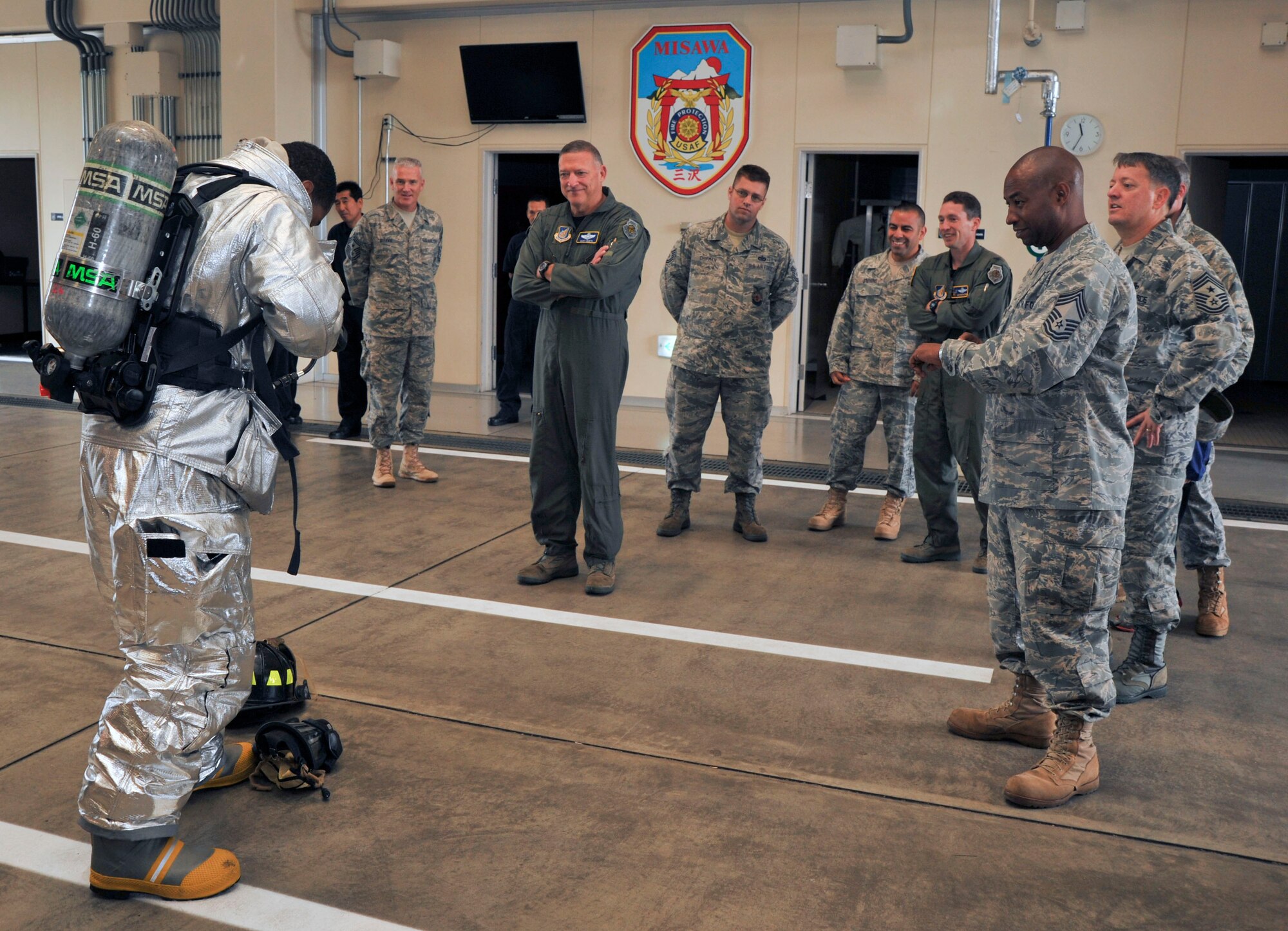 Gen. Gary North, Pacific Air Forces commander, center, watches Senior Airman Timothy Spears, 35th Civil Engineer Squadron, left, don his bunker gear. Airman Spears took less than one minute to don his gear as Chief Master Sgt. McHudson Theodore, 35 CES, right, timed the event during the general's visit to Fire Station 1 at Misawa Air Base, Japan, Sept. 23, 2010. (U.S. Air Force photo by Tech. Sgt. Russell McBride/Released) 