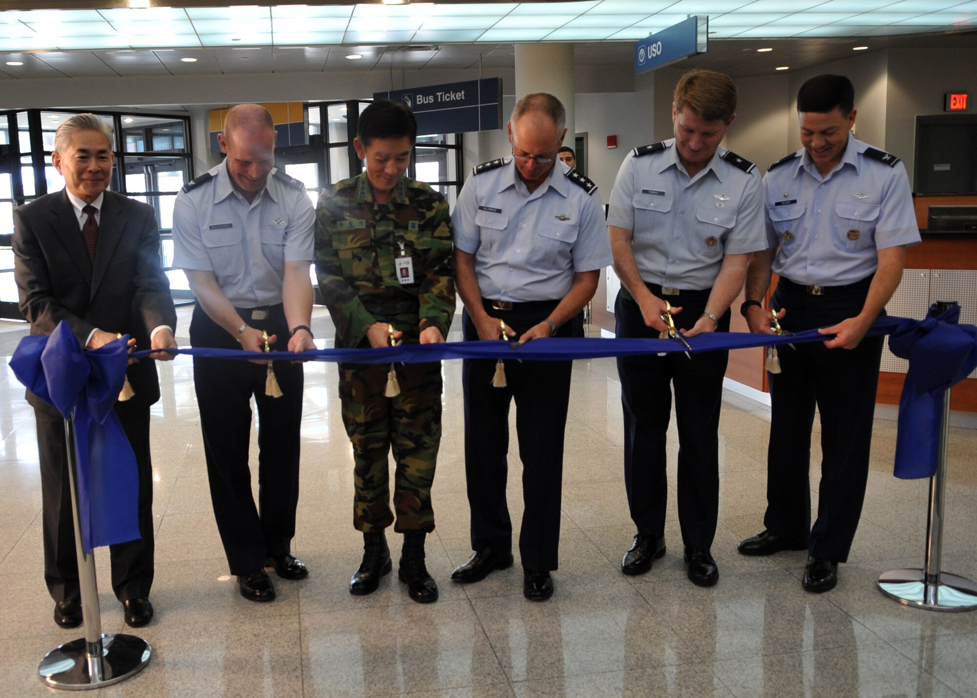 (L-R) Mr. Jon Iwata, U.S. Army Corps of Engineers, Far East District; Col. Patrick C. Malackowski, 51st Fighter Wing commander; Col. Bong-Wan Han, Construction Management team chief, Defense Installation Agency; Lt. Gen. Robert Allardice, 18th Air Force commander; Brig. Gen. Robert Thomas, 15th Expeditionary Mobility Task Force commander; and Col. Stephen Olivernew, 515th Air Mobility Operations Wing commander, cut the ribbon during a ceremony at the new Osan passenger terminal Sept. 27. The event concluded with refreshments and a tour of the facility. (U.S. Air Force photo/Senior Airman Evelyn Chavez)