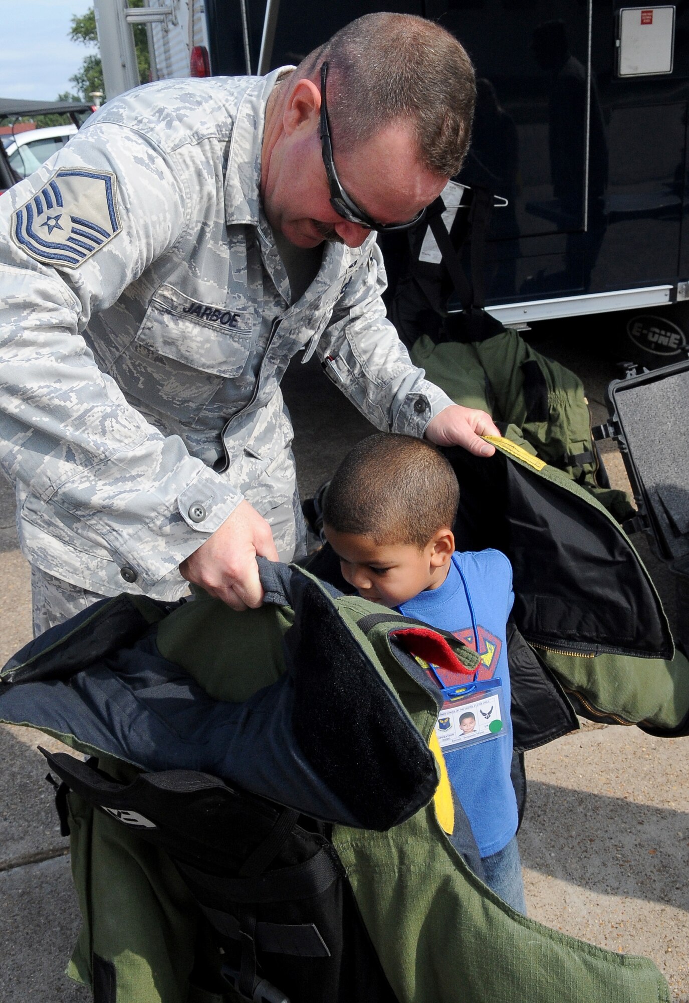 BARKSDALE AIR FORCE BASE, La. -- Master Sgt. Joseph Jarboe, 2nd Civil Engineer squadron, helps a child into part of a bomb suit explosive ordinance disposal Airmen wear, during Operation Hero, Sept. 25. More than 130 children and 90 parents participated in the mock-deployment line to help children understand what their military parents experience before deploying downrange. Some activities included a weapons qualification with paintball guns, chemical readiness preparation and a physical fitness assessment. (U.S. Air Force photo/Senior Airman Amber Ashcraft) (RELEASED)