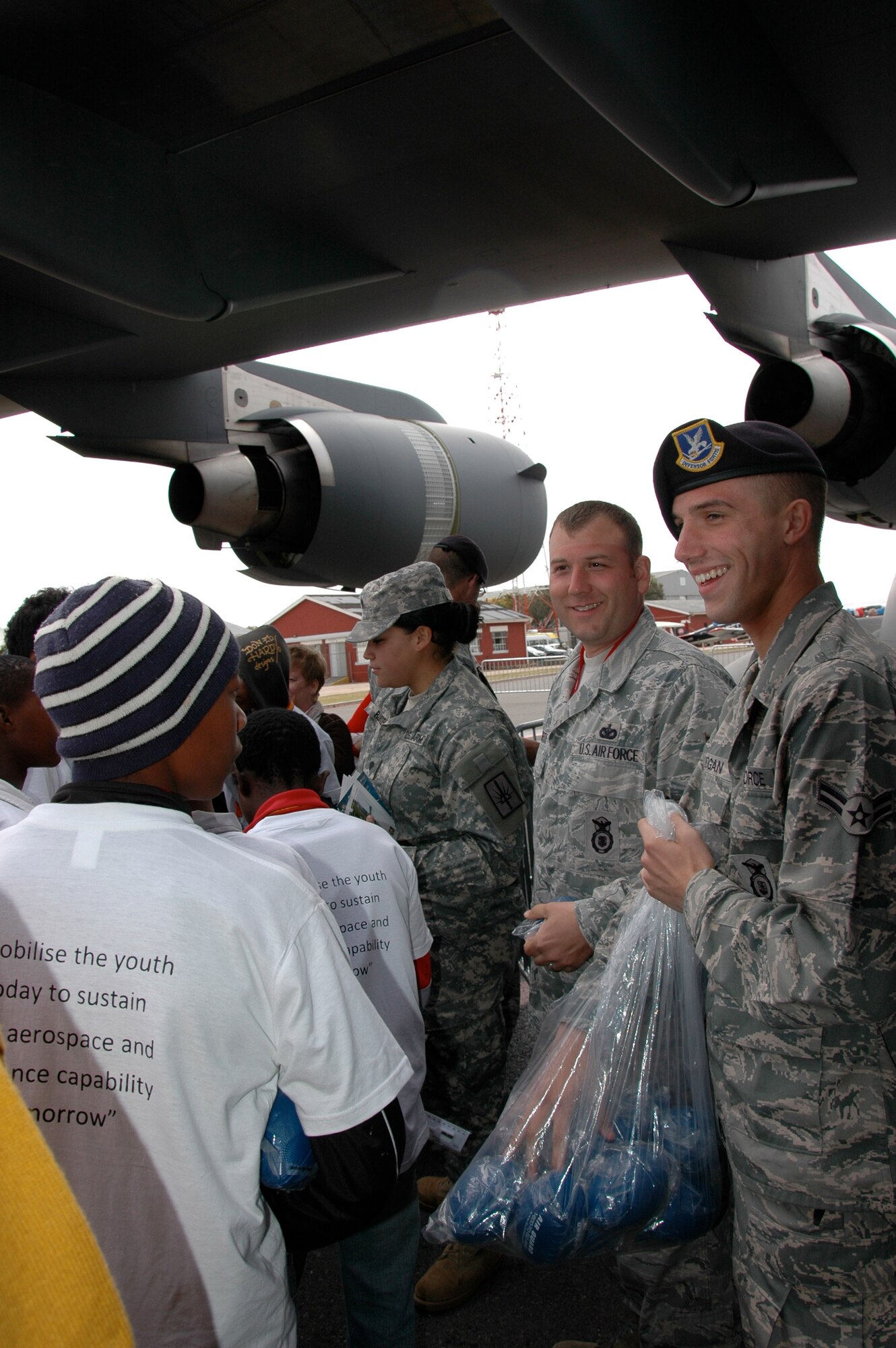 Airman 1st Class Tyler Berogan and Tech. Sgt. Jeffery Griffith, 17th Air Force, Ramstein Air Force Base, Germany, hand out gifts to students attending the 2010 Africa Aerospace and Defense Expo Sept. 23 at Ysterplaat Air Force Base, Cape Town South Africa. Students were invited to be part of the Youth Development Program during the air and trade expo where they learned about opportunities in aviation and defense industries. (U.S. Air Force photo/2nd Lt. Joe Simms)