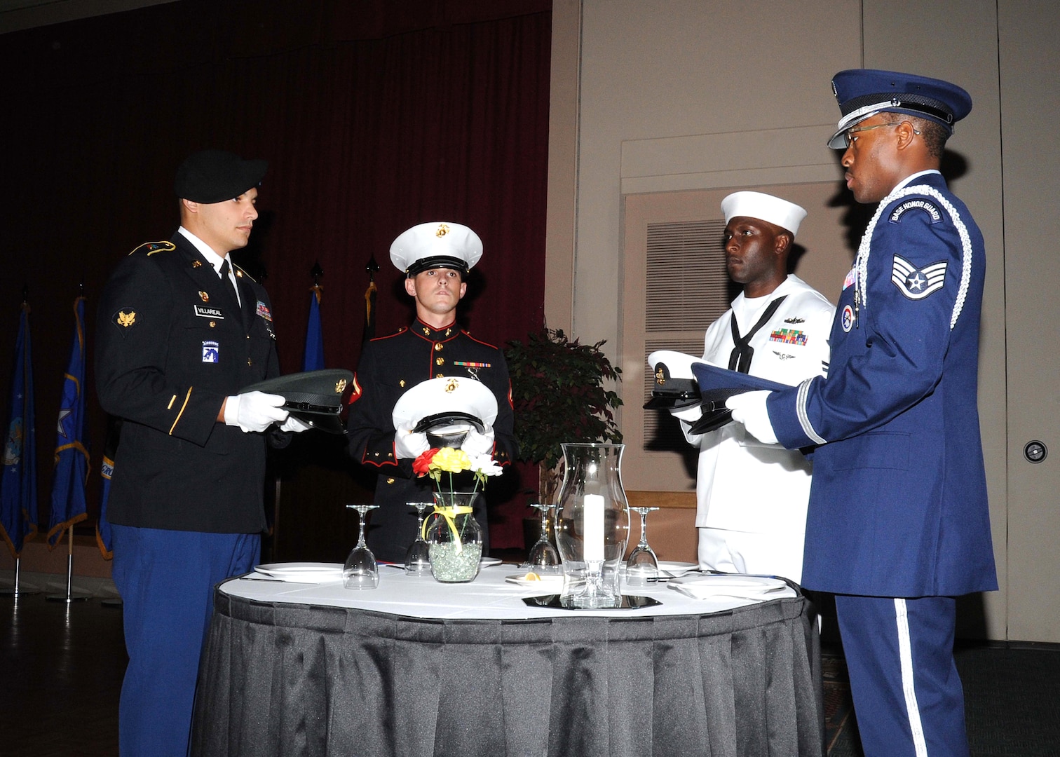 Servicemembers place one hat from each service branch on the Prisoner of War/Missing in Action table during the 502nd Air Base Wing Air Force Ball Sept. 24 at the Gateway Club. The POW/MIA table symbolizes those lost in combat who could not share in the celebration. (U.S. Air Force photo/Alan Boedeker) 