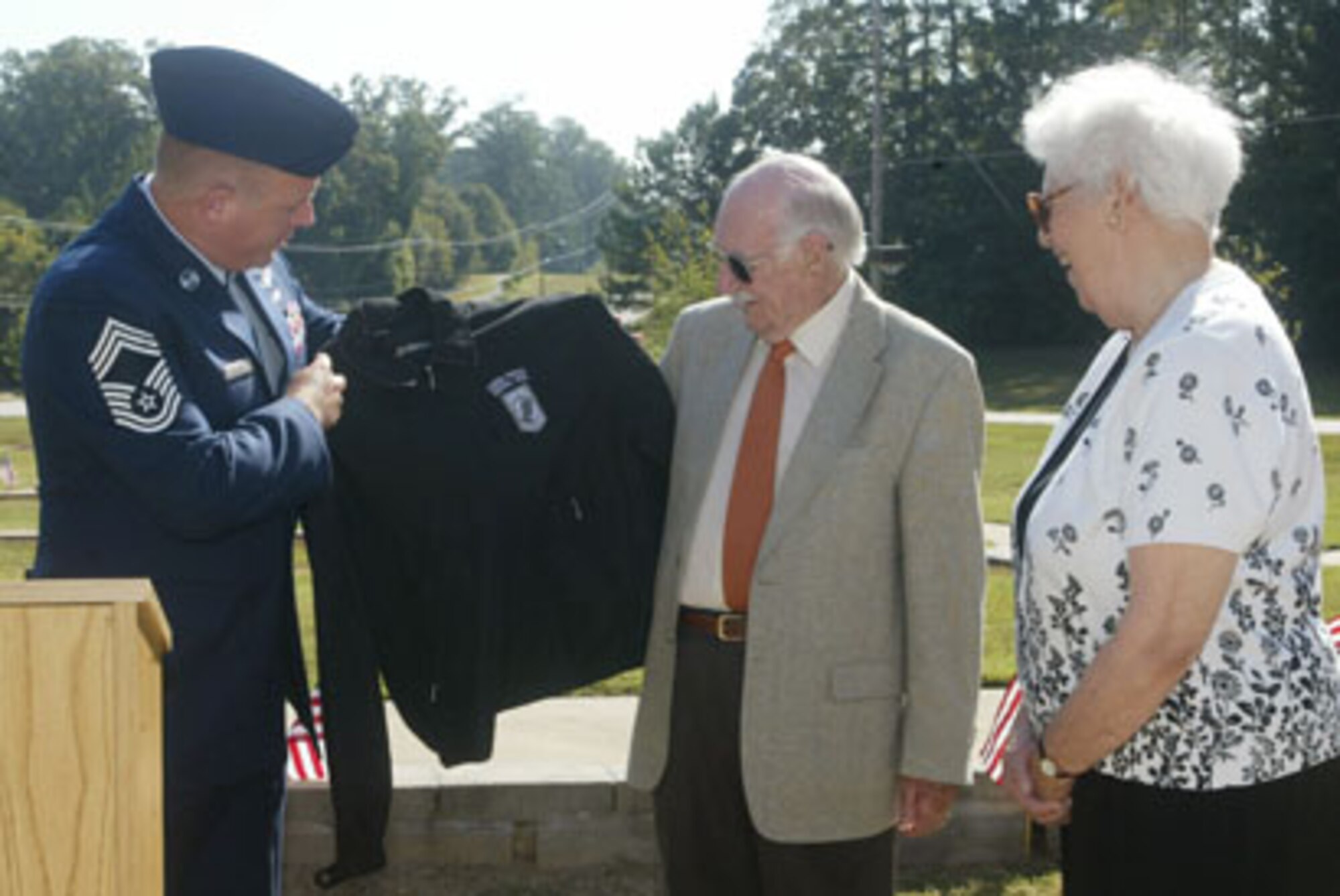 Chief Master Sgt. Michael McDonald president of the Dobbins Chiefs Group presents Ronald Pearce with a jacket with the POW/MIA logo after Pearce an Australian Air Force Bombardier, shared his experience of escaping and evading German Forces after being shot down at the beginning of World War II with a crowd attending the 26th Annual Living Memorial Ceremony held at the POW/MIA Memorial Park here Sep 24. (U.S. Air Force photo/Don Peek) 