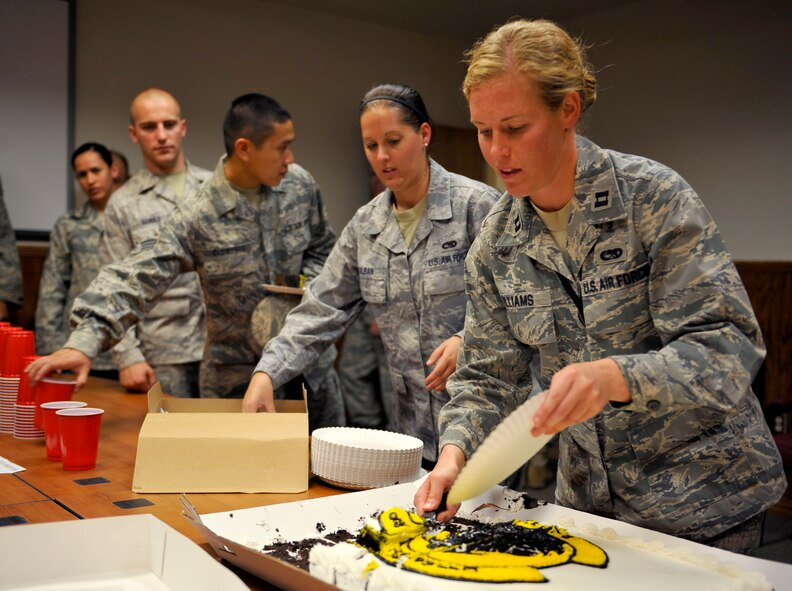 HOLLOMAN AIR FORCE BASE, N.M. -- Capt. Jessica Williams, 8th Aircraft Maintenance Unit, cuts a slice of cake at the opening ceremony of the 8th AMU building, Sept. 16, 2010. Airmen from the 8th AMU were invited to eat cake and take a tour of the newly renovated building. The 8th AMU invested $2 million toward the renovation of their building where they can continue their support for F-22 operations. (U.S. Air Force photo by Senior Airman Veronica Stamps / Released)