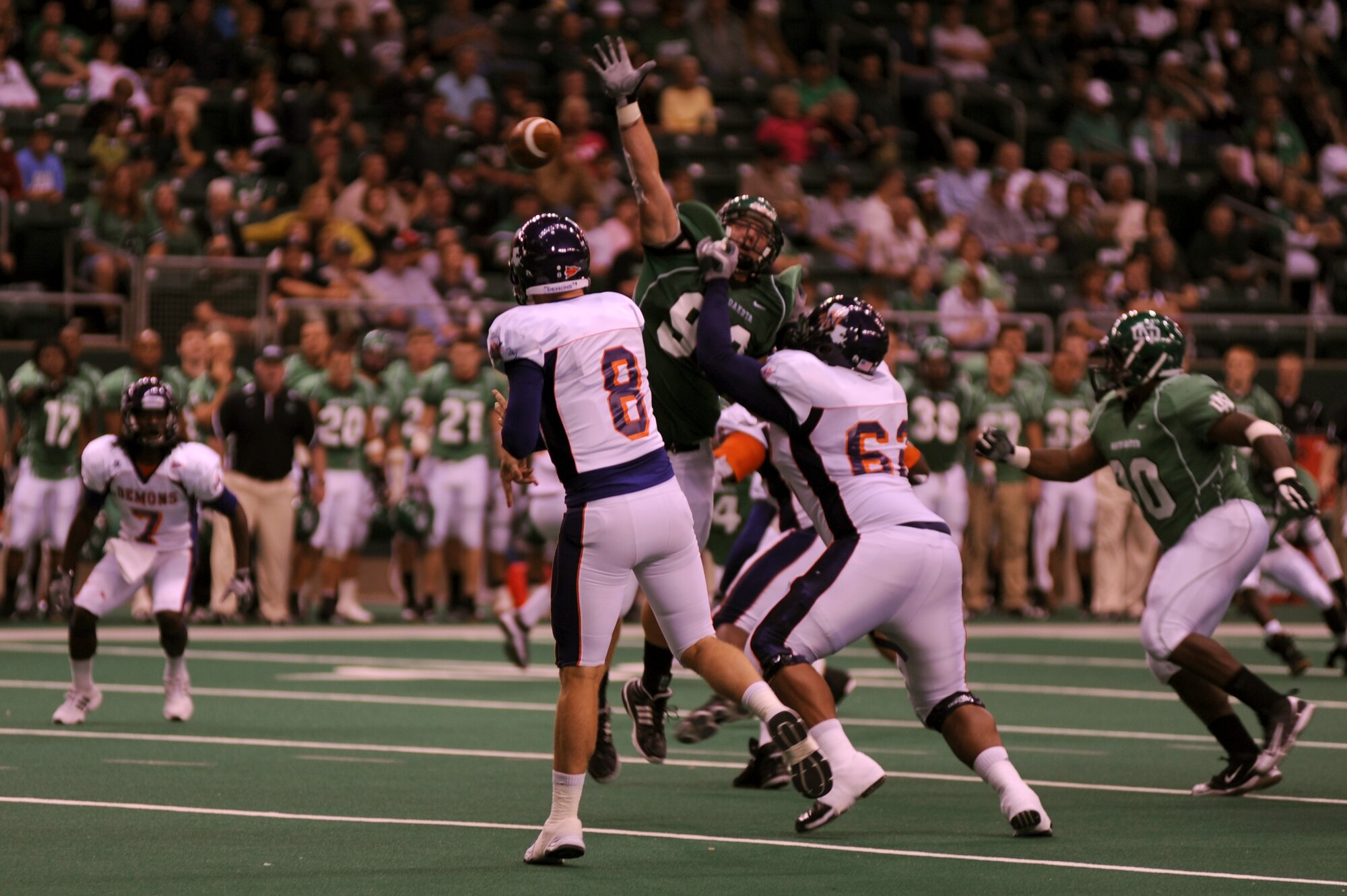 Players from Northwestern State University (white jersey) attempt to complete a pass while being rushed by players from the University of North Dakota (green jersey) football player during the UND military appreciation football game Sept. 25 at the Alerus Center in Grand Forks, N.D. The Grand Forks Chamber of Commerce Military Affairs Committee supplied food and tickets to military members and their families. The UND Fighting Sioux defeated the NSU Demons 49-24. (U.S. Air Force photo by Senior Airman Amanda N. Stencil)