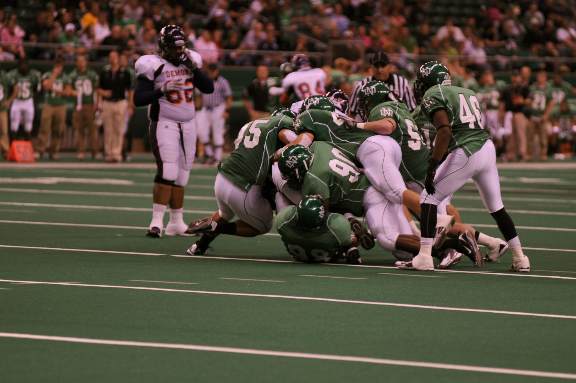 Players from the University of North Dakota football team (green jersey) tackle a member of Northwestern State University Demons during the military appreciation football game Sept. 25 at the Alerus Center in Grand Forks, N.D. The Grand Forks Chamber of Commerce Military Affairs Committee supplied food and tickets to military members and their families. The UND Fighting Sioux defeated the NSU Demons 49-24. (U.S. Air Force photo by Senior Airman Amanda N. Stencil)