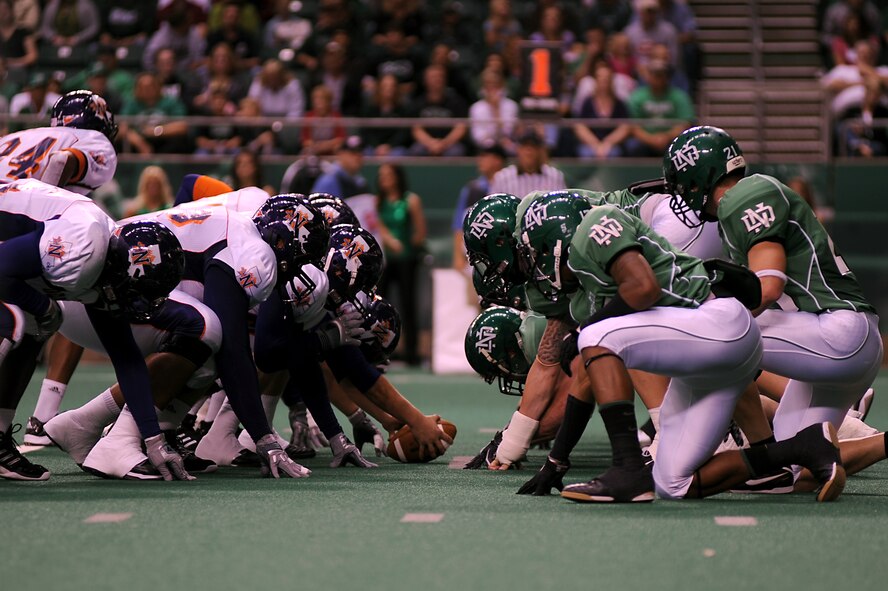 The Northwestern State University Demons (white jersey) and the University of North Dakota Fighting Sioux (green jersey) prepare for the Demons to hike the ball during the UND military appreciation football game Sept. 25 at the Alerus Center in Grand Forks, N.D. The Grand Forks Chamber of Commerce Military Affairs Committee supplied food and tickets to military members and their families. The UND Fighting Sioux defeated the NSU Demons 49-24. (U.S. Air Force photo by Senior Airman Amanda N. Stencil)