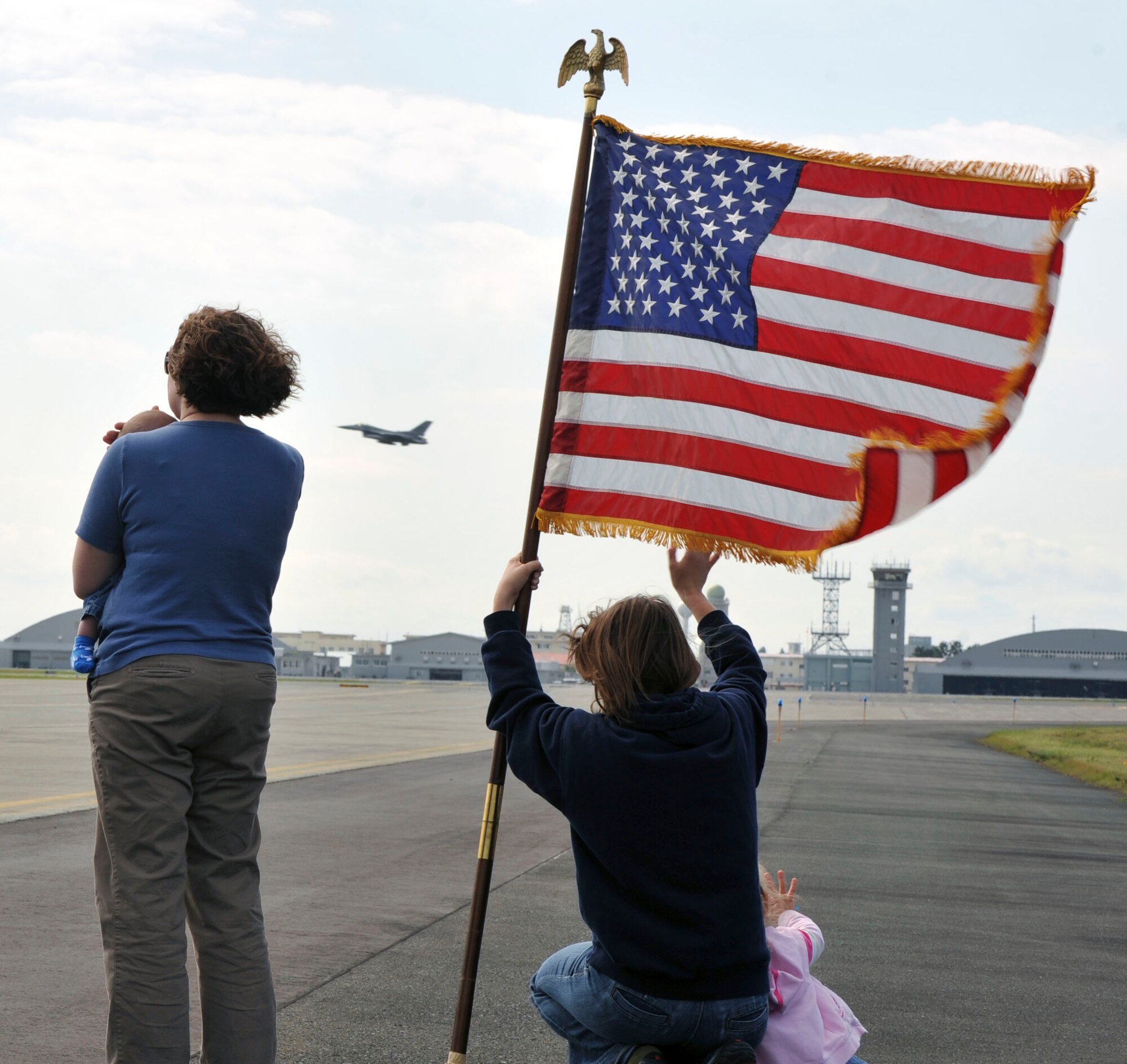 Jenny Cichowsky, left, wife of U.S. Air Force Capt. Trevor Cichowski, 13th Fighter Squadron and Laura Breau, center, wife of U.S. Air Force Capt. Jesse Breau 13 FS wave to members of the 13 FS as they leave Misawa Air Base, Japan for a deployment. Sept. 27. 2010. Traditionally, spouse of the deploying members gather at the flightline to watch the pilots fly away. (U.S. Air Force photo by Tech. Sgt. Russell McBride/Released)