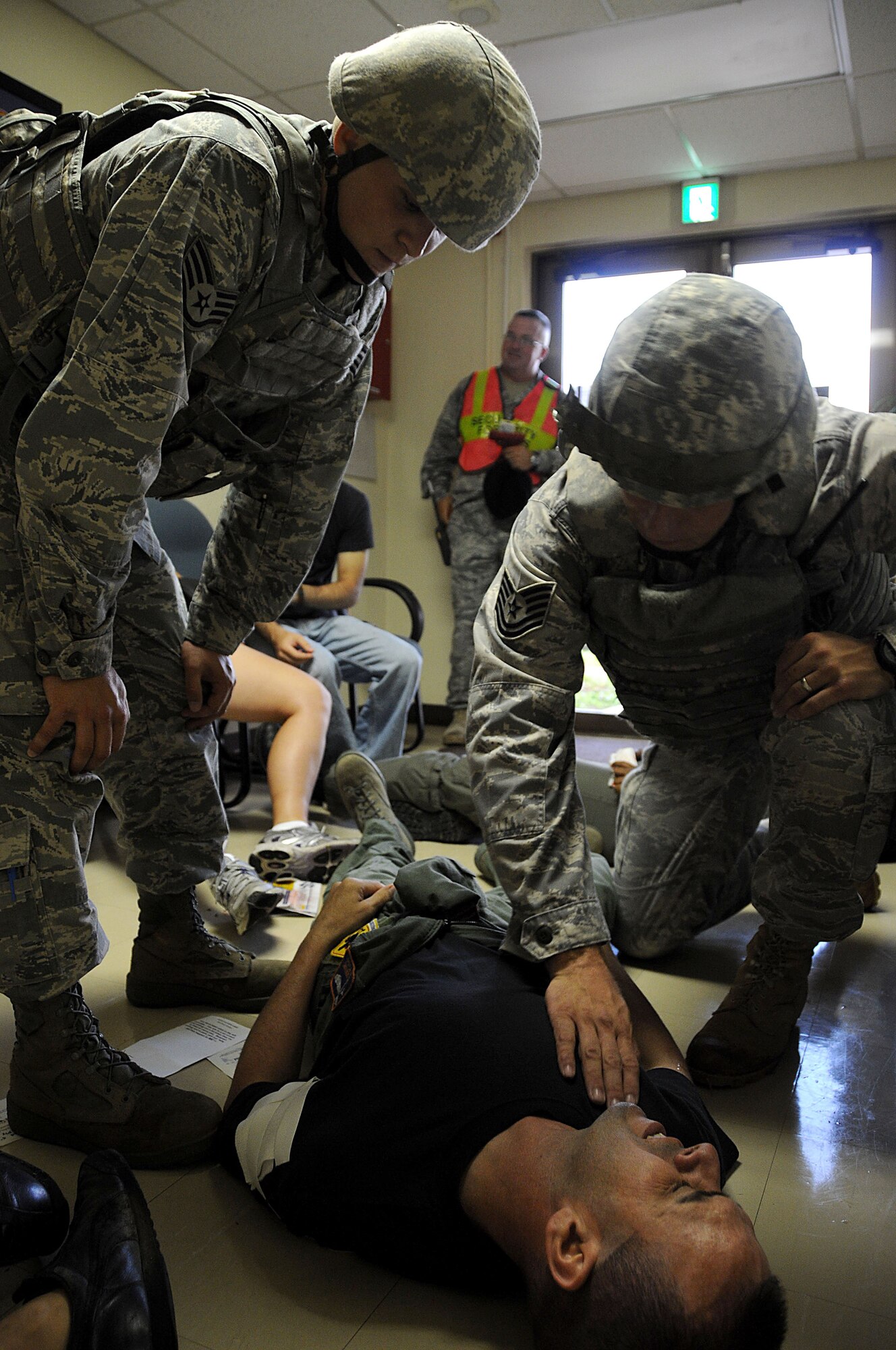 Staff Sergeants Kyle Billings and John Smith, 18th Security Force Squadron members, check the vital signs of an injured bystander during an exercise at Kadena Air Base, Japan, Sept. 28. This exercise tested the 18th Wing's ability to respond to a simulated "shots fired" scenario. (U.S. Air Force photo/Staff Sgt. Darnell T. Cannady)