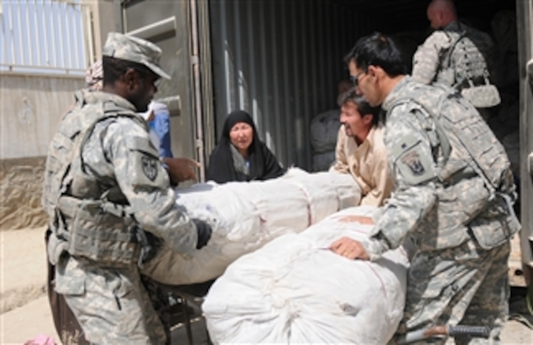 U.S. Army soldiers with 1st Battalion, 101st Field Artillery Regiment, Massachusetts Army National Guard, assist an Afghan family with tents and food supplies during the delivery of humanitarian aid in the Dasht Barchi village of Kabul, Afghanistan, on Sept. 23, 2010.  The soldiers partnered with Afghan National Police to procure and deliver shelter and food to families whose homes were damaged by flooding.  