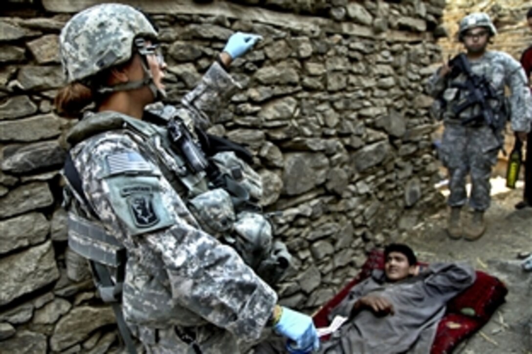 A U.S. Army soldier prepares to treat an injured Afghan man in Masamute Bala in Laghman province, Afghanistan, as the village is cordoned and searched, Sept. 25, 2010. The soldier is assigned to the 1st Battalion, 102nd Infantry Regiment, 86th Brigade Combat Team.