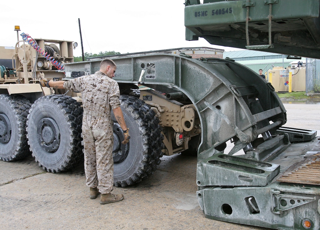 Lance Cpl. Antonio Schiaffino, a logistics vehicle system operator with Marine Wing Support Group 17, 1st Marine Aircraft Wing, I Marine Expeditionary Force, guides the connection of a Logistics Vehicle System Replacement MKR 16 tractor to a trailer loaded with a scraper-tractor as part of a loading test aboard Marine Corps Base Camp Lejeune, N.C., Sept. 28, 2010. Marines from all three Marine Expeditionary Forces worked together to properly field test two new logistics vehicles that the Marine Corps is researching.