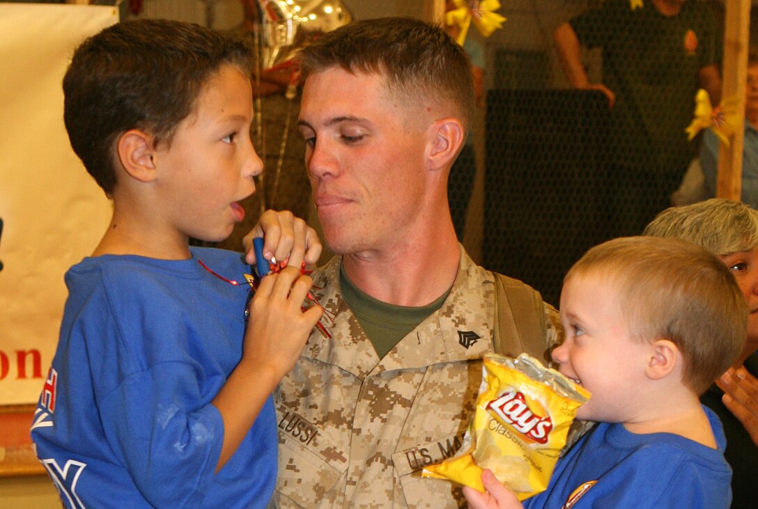 Sgt. Aaron Lussi, a Marine from 1st Battalion, 2nd Marine Regiment, holds his children after his unit was dismissed following their return from Helmand Province Afghanistan.  Lussi and his unit returned from their seven-month deployment to sounds of cheers and applause, Sept. 29.