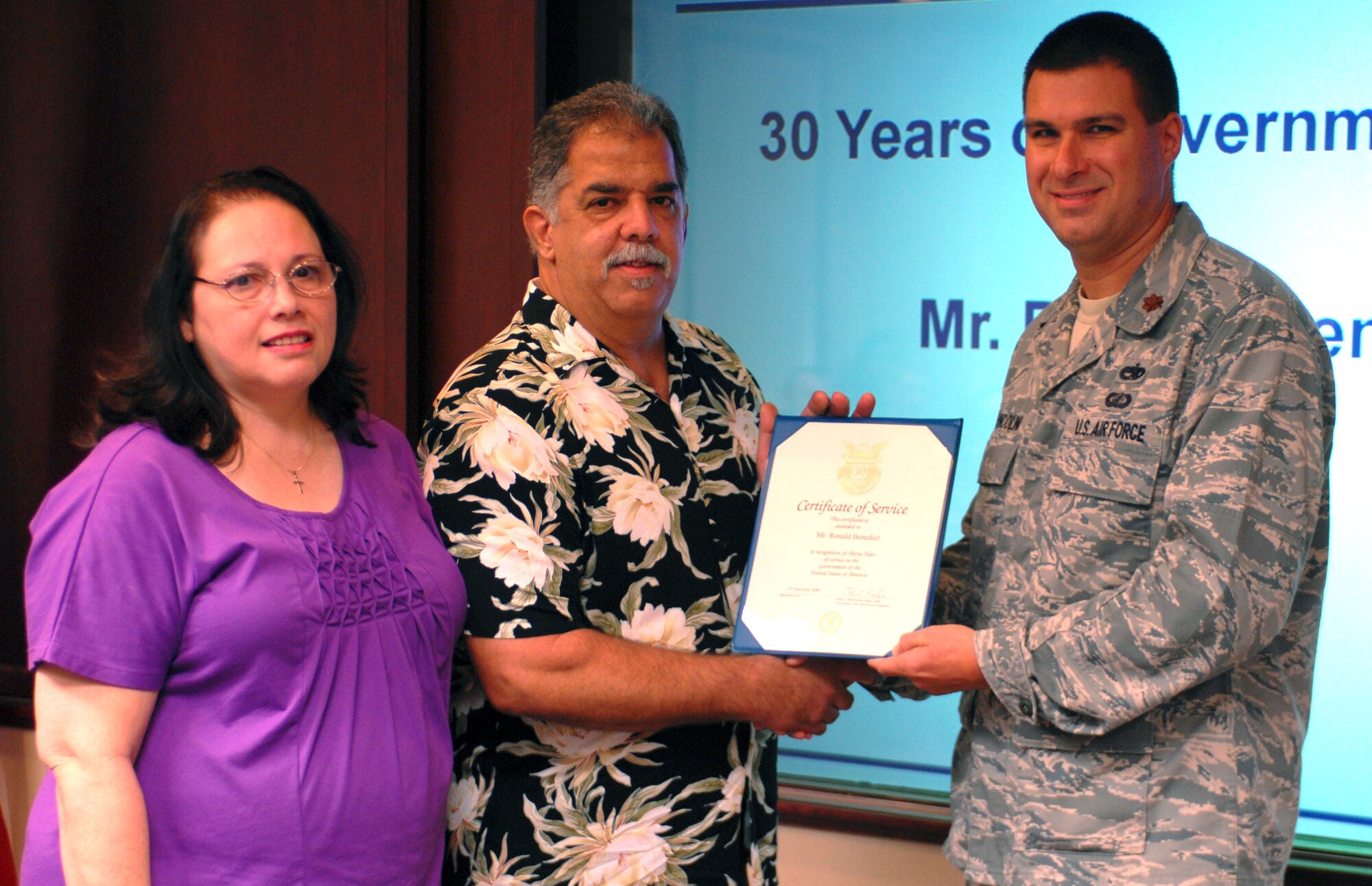 Maj. John Francolini, commander for both the 15th Maintenance Operations Squadron and 15th Maintenance Squadron, presents Ron Benedict, 15th MXS aerospace ground equipment mechanic, and his wife Barbara, with a certificate honoring Ron's 30 years of civil service Sept. 22 at the 15th Wing headquarters building. (U.S. Air Force photo by Senior Airman Gustavo Gonzalez)
