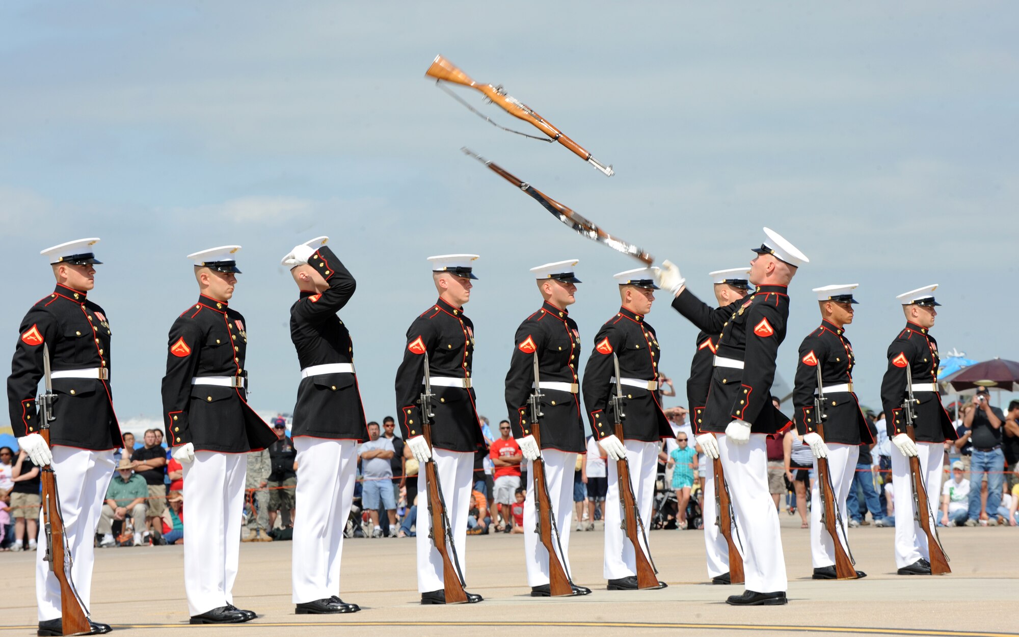 A crowd watches as the U.S. Marine Corps Silent Drill Platoon perform a rifle-toss during McConnell’s 2010’s Open House and Air Show Sept. 25, 2010, McConnell Air Force Base, Kan.  The platoon dates back to 1948; since then, they have performed nationwide at ceremonies and military air shows. The members of the platoon are hand-selected from infantry schools and serve a two-year ceremonial tour.  (U.S. Air Force photo/Airman 1st Class Andrea Salazar)