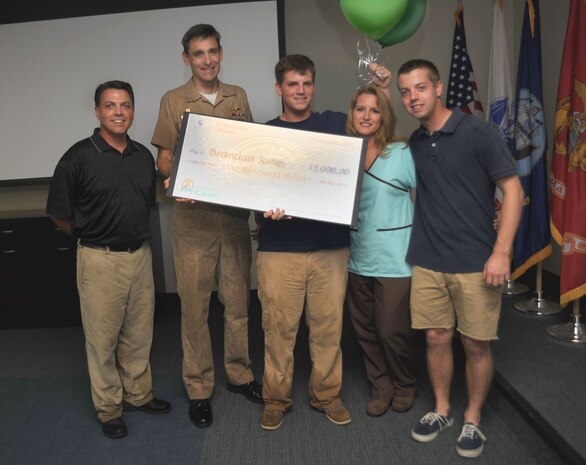Navy Capt. Ralph Ward presents Brandon Jones with a scholarship check for $1,000 toward his college education during the Wing Stand-Up meeting on Joint Base Charleston, Sept. 27, 2010. Brandon graduated in the top 10 percent of his class from Fort Dorchester High School and recently began higher education at the College of Charleston. The scholarship was sponsored by the Air Force Clubs. This is the 14th year in a row that the Club has awarded scholarships totaling $25,000. Brandon won his scholarship with an essay titled, ?What the Air Force family means to me.? Twenty-five winners were selected from 130 entries submitted by numerous installations. Brandon hails from a family that is rich with Air Force heritage. Brandon's parents, Brian and Lisa Jones are both civilian employees on JB CHS and his brother, Airman 1st Class Brian Jones Jr.is a loadmaster with the 315th Airlift Squadron. Captain Ward is the Joint Base Charleston deputy commander. (U.S. Air Force photo/Airman 1st Class Lauren Main)