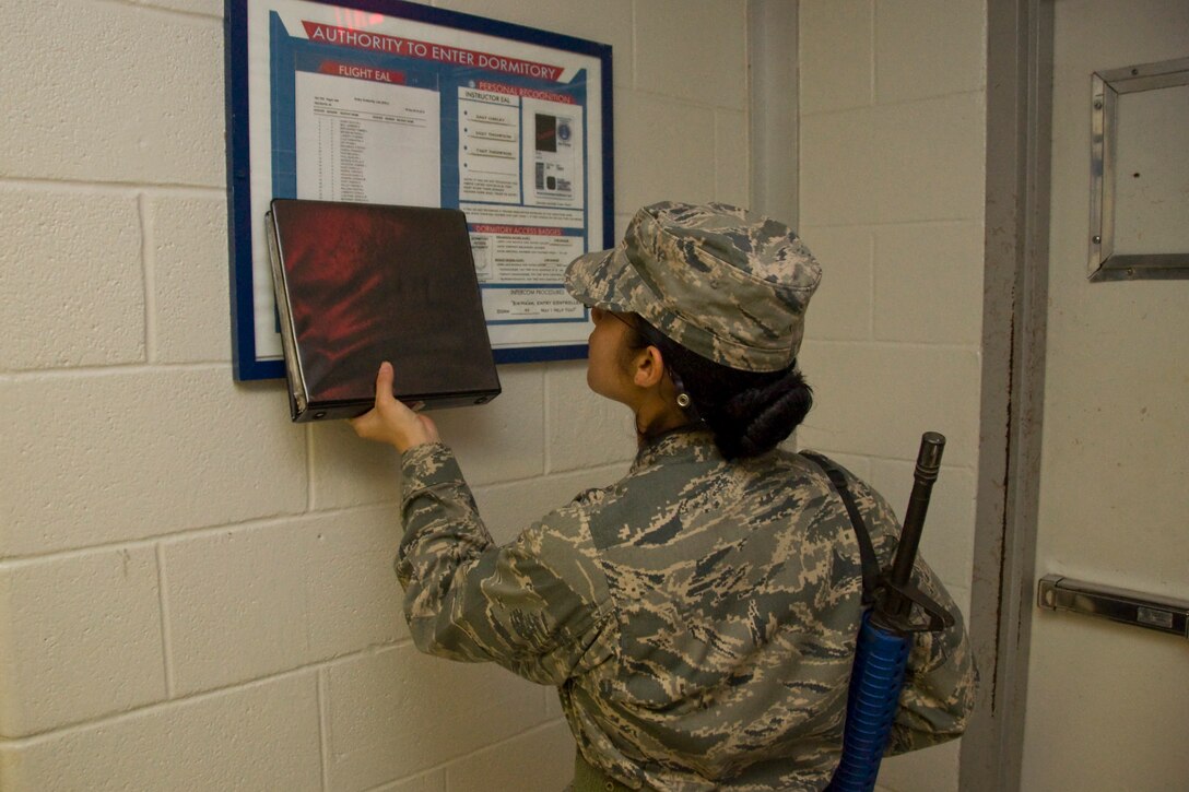 Trainee conducting entry controller duties as she verifies dormitory access procedures. (U.S. Air Force Photo/Melinda Mueller)
