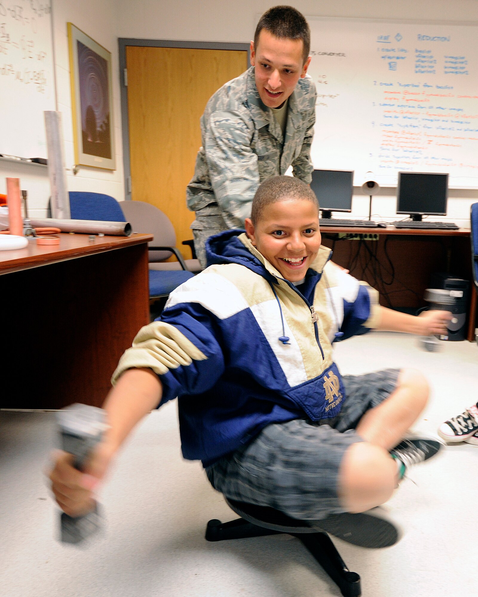 Cadet 4th Class Richard Cook and Trevor Hobson demonstrate inertia in a rotating frame of reference during a tour of the Air Force Academy's Department of Physics and observatory Sept. 24, 2010. Trevor is a student at Falcon Middle School in Colorado Springs, Colo. (U.S. Air Force photo/Mike Kaplan)