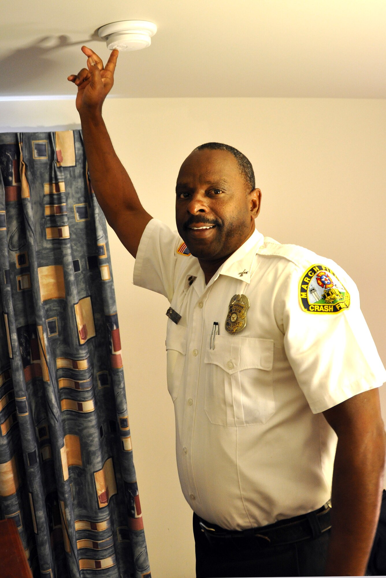 In the fire chief's bunkroom Sept. 27, 2010, Timothy Williams, a fire inspector with the March Air Reserve Base Fire Department, demonstrates the simple but crucial task of testing fire detectors every month. (U.S. Air Force photo/ Megan Just)