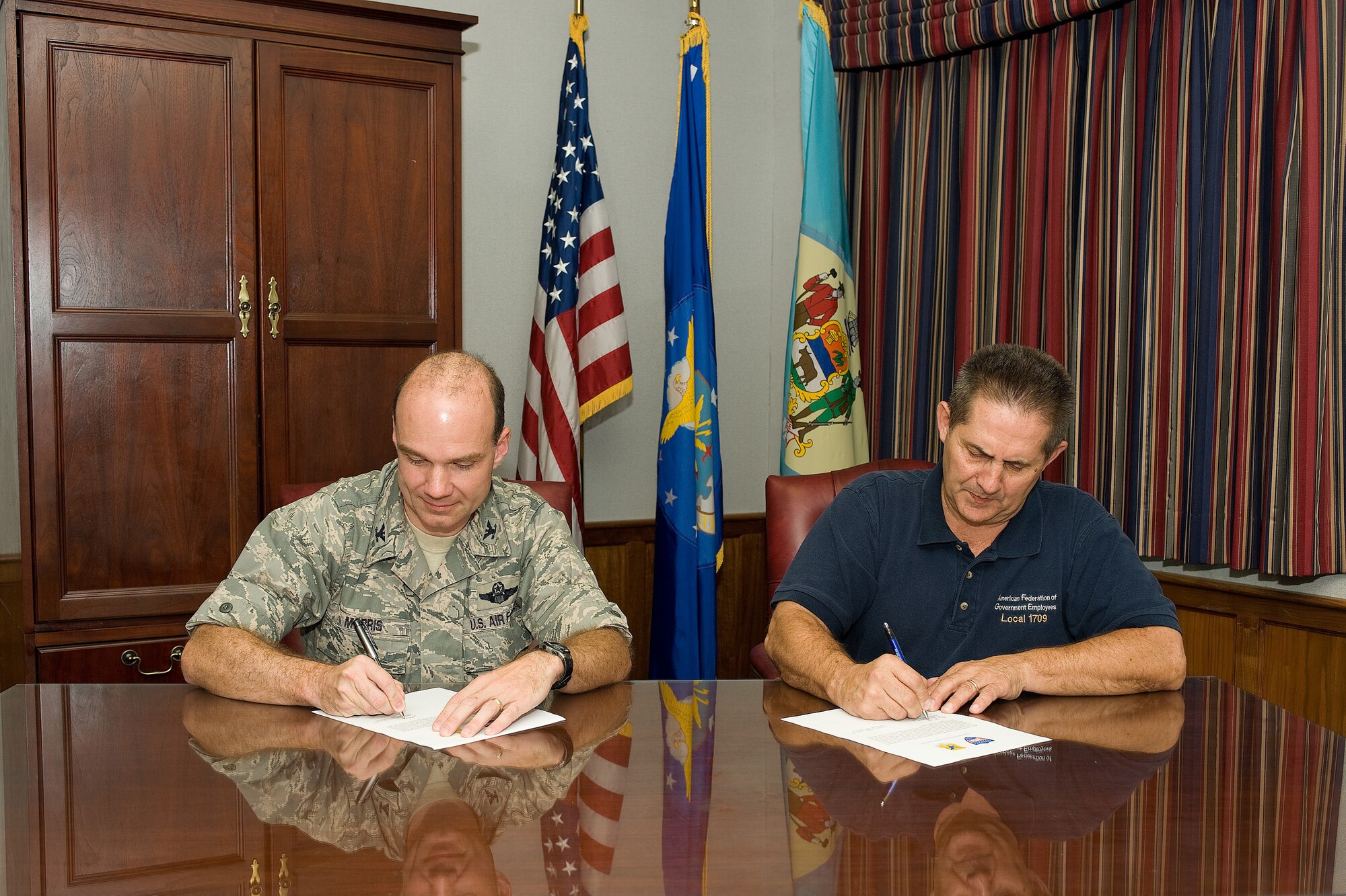 Col. Manson Morris, 436th Airlift Wing commander, and Brent Reynolds, American Federation of Government Employees Local 1709 president, sign a commitment letter for Occupational Safety and Health Administration's Voluntary Protection Program at Dover Air Force Base, Del., Sept. 23, 2010. This letter will create a partnership between the wing and the union in order to foster a safety culture that focuses on employee involvement. (U.S. Air Force photo by Jason Minto/Released)