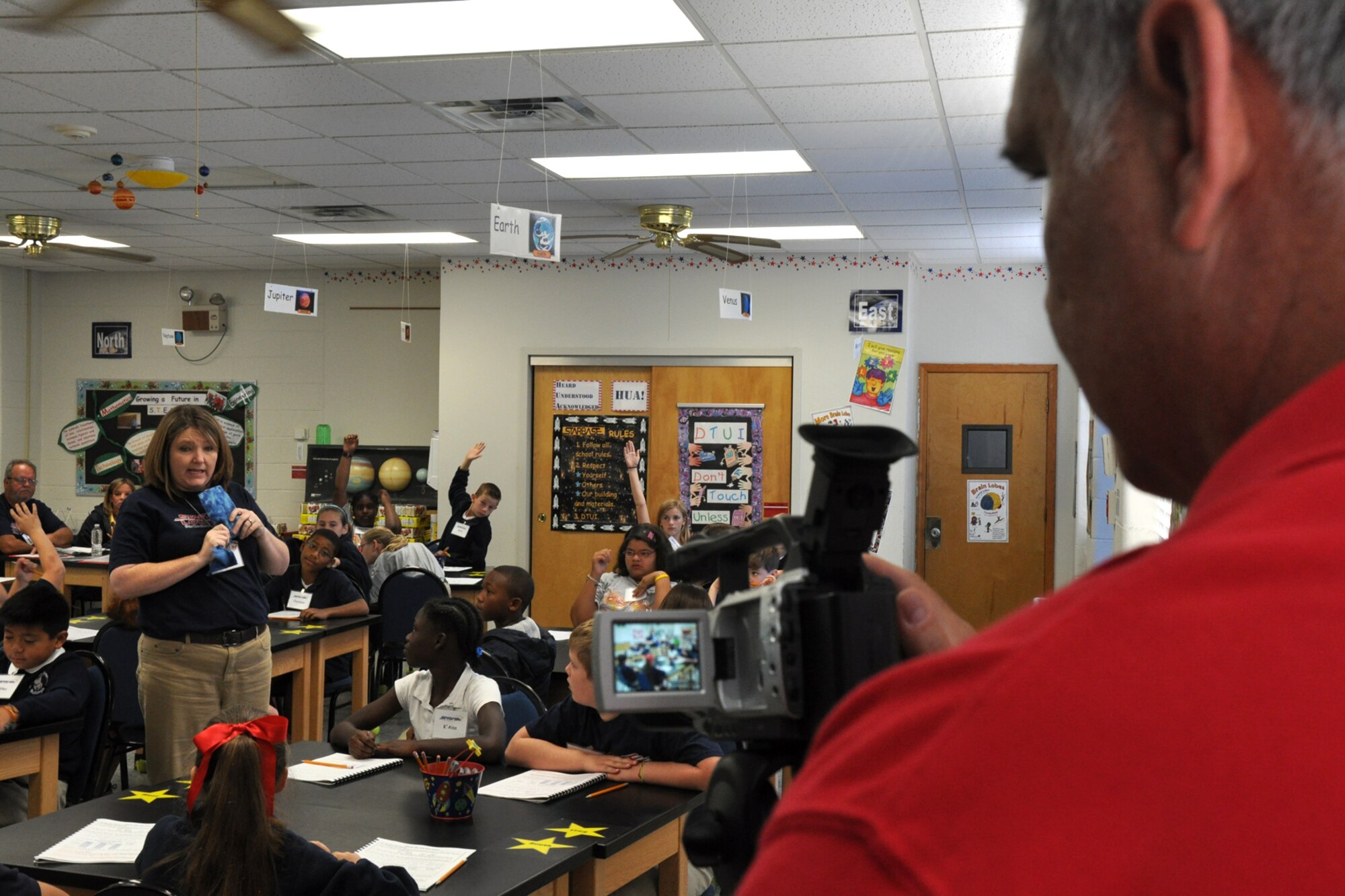 Greg Steele, visual information specialist for the 917th Wing, videotapes Ms. Christy Bucker, in a STARBASE classroom as she explains to a group of 5th Graders chemical reactions that produce different degrees of temperature, Sept. 28, 2010. Ms. Bucker is a program instructor. STARBASE Louisiana recently completed more than 10 years of service, graduating more than 10,000 students. The facilities have recently been upgraded, and the Grand Reopening event will be held on Oct. 18, 2010, at the STARBASE facility to celebrate and showcase the benefits of STARBASE and its history of support from the educational, military, and corporate communities, and its proven track record of raised student performance and increased interest in S.T.E.M. subjects. (U.S. Air Force photo/Tech. Sgt. Jeff Walston) 