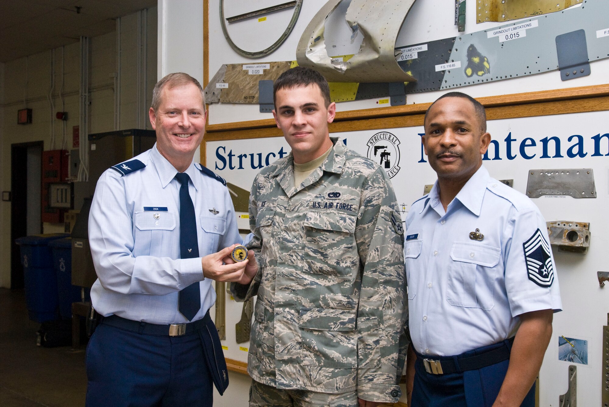 Col. Michael Zick (left), 19th Airlift Wing vice commander, and Chief Master Sgt. Stephen Gregory (right), 19th AW Director’s Staff superintendent, present a coin Monday to Airman 1st Class Robert Ice, 19th Equipment Maintenance Squadron aircraft structural maintenance apprentice, for his selection as the Combat Airlifter of the Week. Airman Ice expedited the repair of two main landing gear tracks, cutting the standard 36-hour completion time by 12 hours and avoided $98,000 in depot-level repairs. (U.S. Air Force photo by Staff Sgt. Nestor Cruz)
