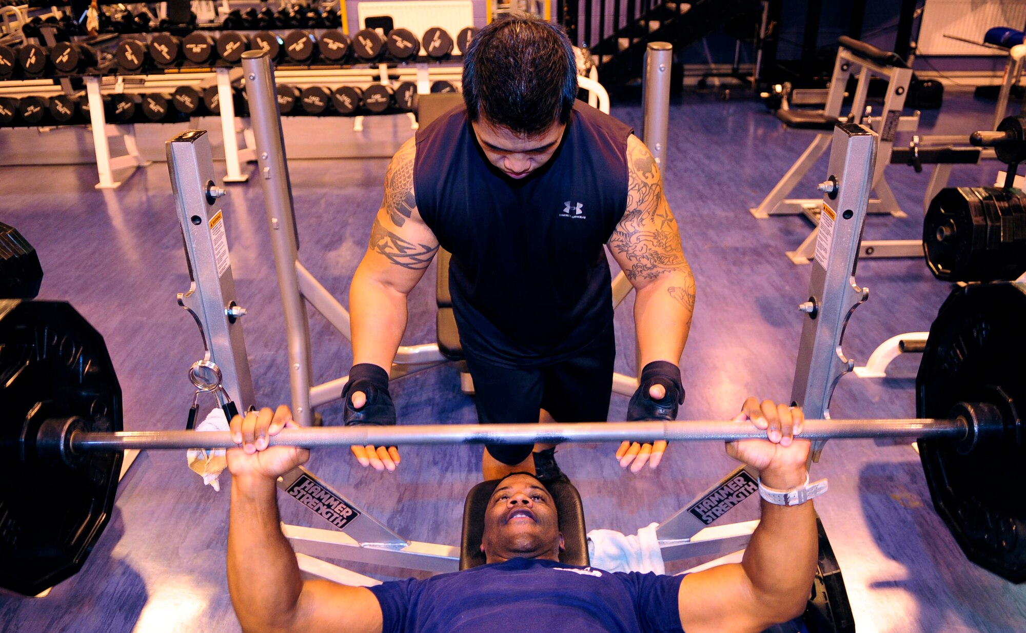 RAF MILDENHALL, England -- Tech. Sgt. Christopher Williams, 100th Logistics Readiness Squadron, performs sets of bench presses at the North Side Fitness Center while spotted by Staff Sgt. Reggie Patterson, also 100th LRS, here Sept. 23.  Spotting for your fellow Airmen while they lift weights is just one of the many ways to be a good wingman. (U.S. Air Force photo/Senior Airman Ethan Morgan)