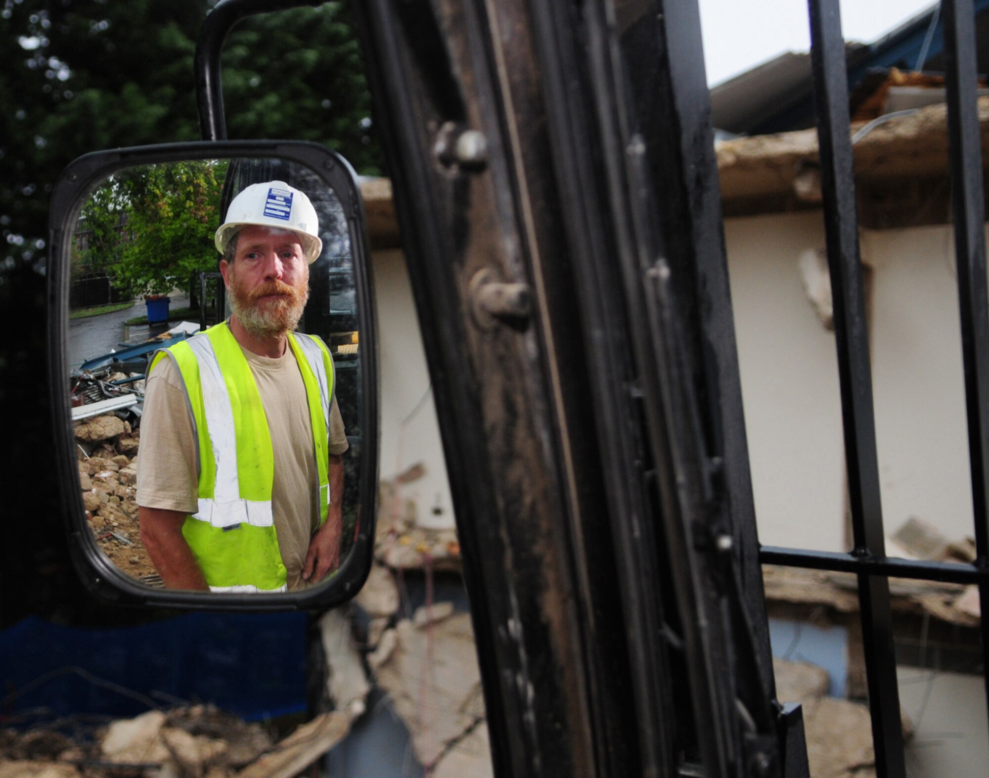 RAF MILDENHALL, England -- JCB driver Rob Saunders, a local contractor, stands on the caterpiller tire of his JCB amidst the rubble of dormitory 212 which is currently being demolished. Mr. Saunders is also demolishing dorm 213, both of which are due to be finished by January 2011. The quality of the Airmen's quarters had deteriorated and had become surplus to requirements. Once demolition is complete, the area will be landscaped. (U.S. Air Force photo/Karen Abeyasekere)