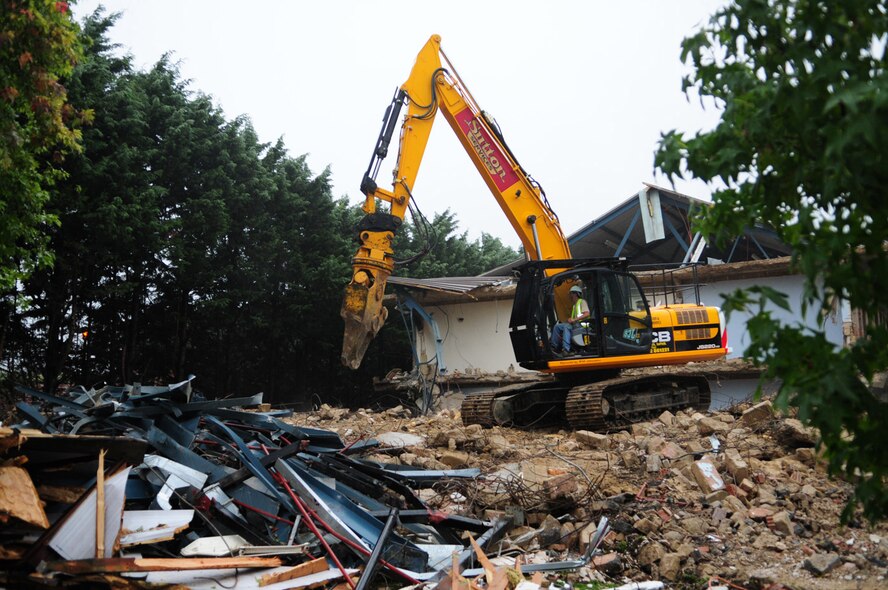 RAF MILDENHALL, England -- Digger driver Rob Saunders, a local contractor, swings his JCB around to drop and pick up old pieces from the wreck of dormitory 212, currently being demolished. The quality of the Airmen's quarters had deteriorated and had become surplus to requirements. Once demolition is complete, which is scheduled for January 2011, the area will be landscaped. (U.S. Air Force photo/Karen Abeyasekere)