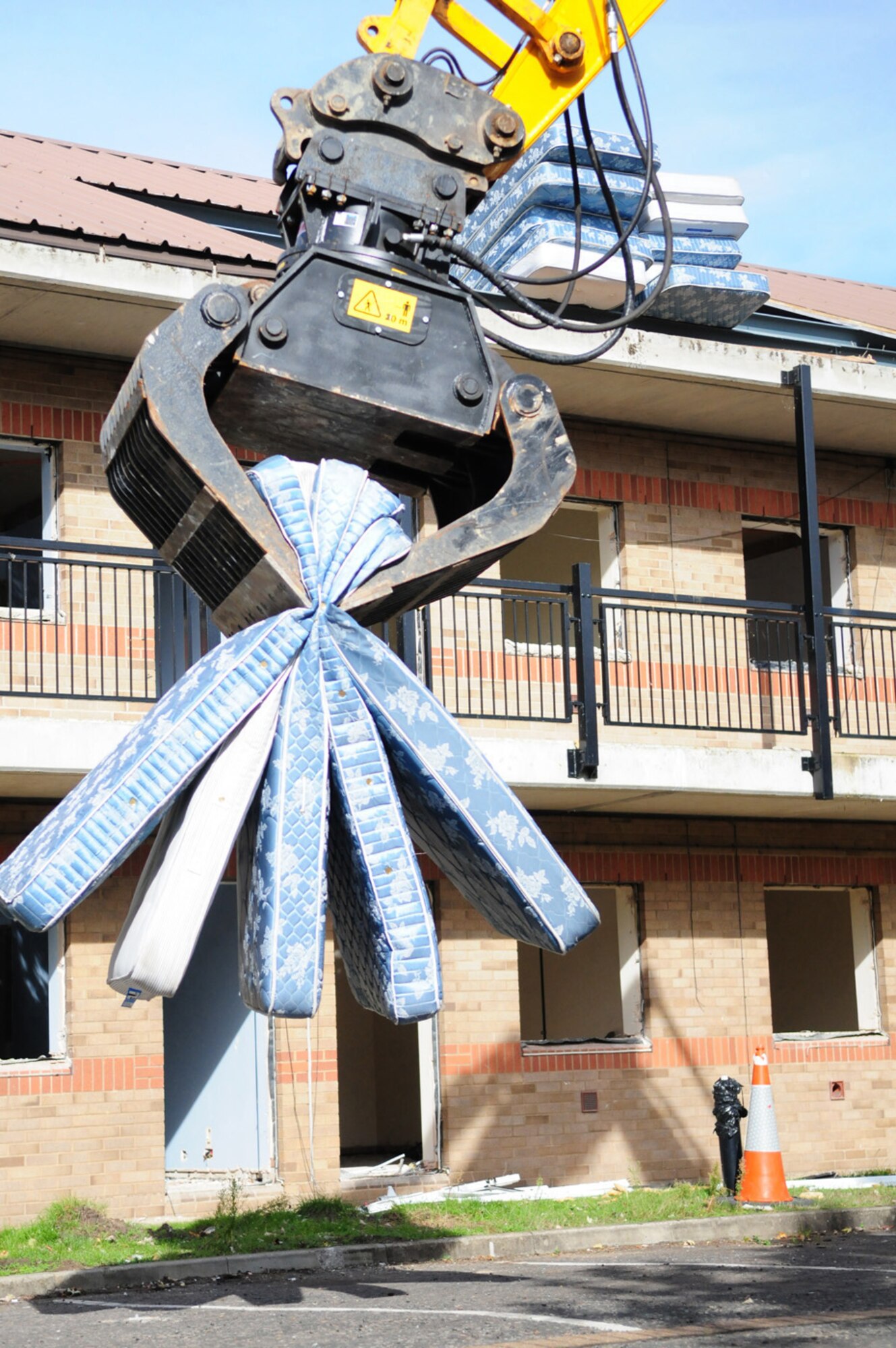 RAF MILDENHALL, England -- A mechanical digger picks up mattresses in its jaws to clear out an old dorm here Sept. 20 before it gets demolished. The quality of the Airmen's quarters had deteriorated and had become surplus to requirements. Once demolition is complete, which is scheduled for January 2011, the area will be landscaped. (U.S. Air Force photo/Karen Abeyasekere)