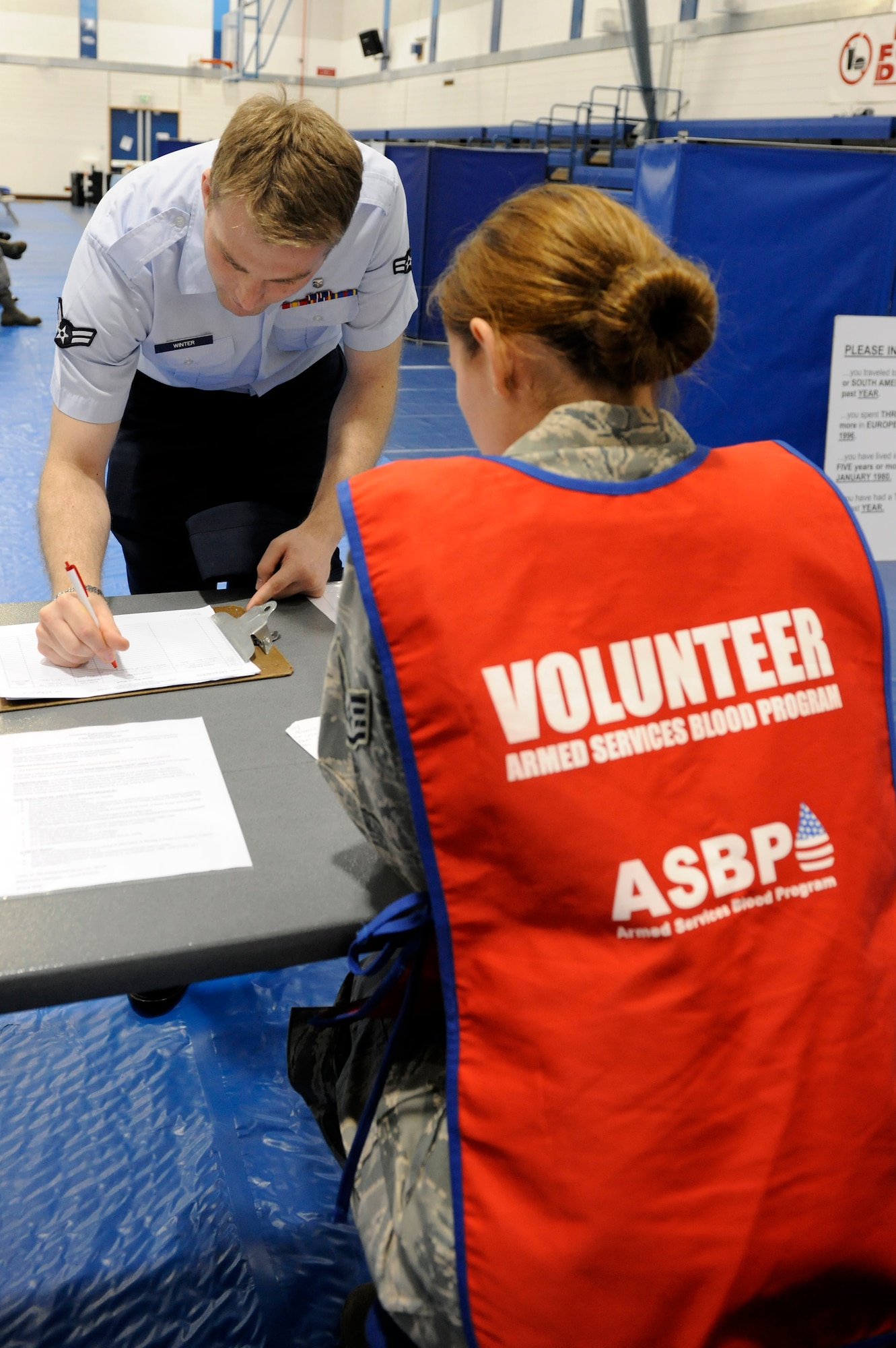ROYAL AIR FORCE LAKENHEATH, England -- Staff Sgt. Lindsay Lalla (right), 48th Medical Logistics Squadron Laboratory technician, oversees Airman 1st Class Sean Winters, 48th Medical Operations Squadron Pediatric medical technician, while he signs in to the the Armed Services Blood Program held at the fitness center Sept. 27.  Sergeant Lalla was one of 13 from RAF Lakenheath who volunteered to help with the blood drive. (U.S. Air Force photo/Airman 1st Class Lausanne Morgan)