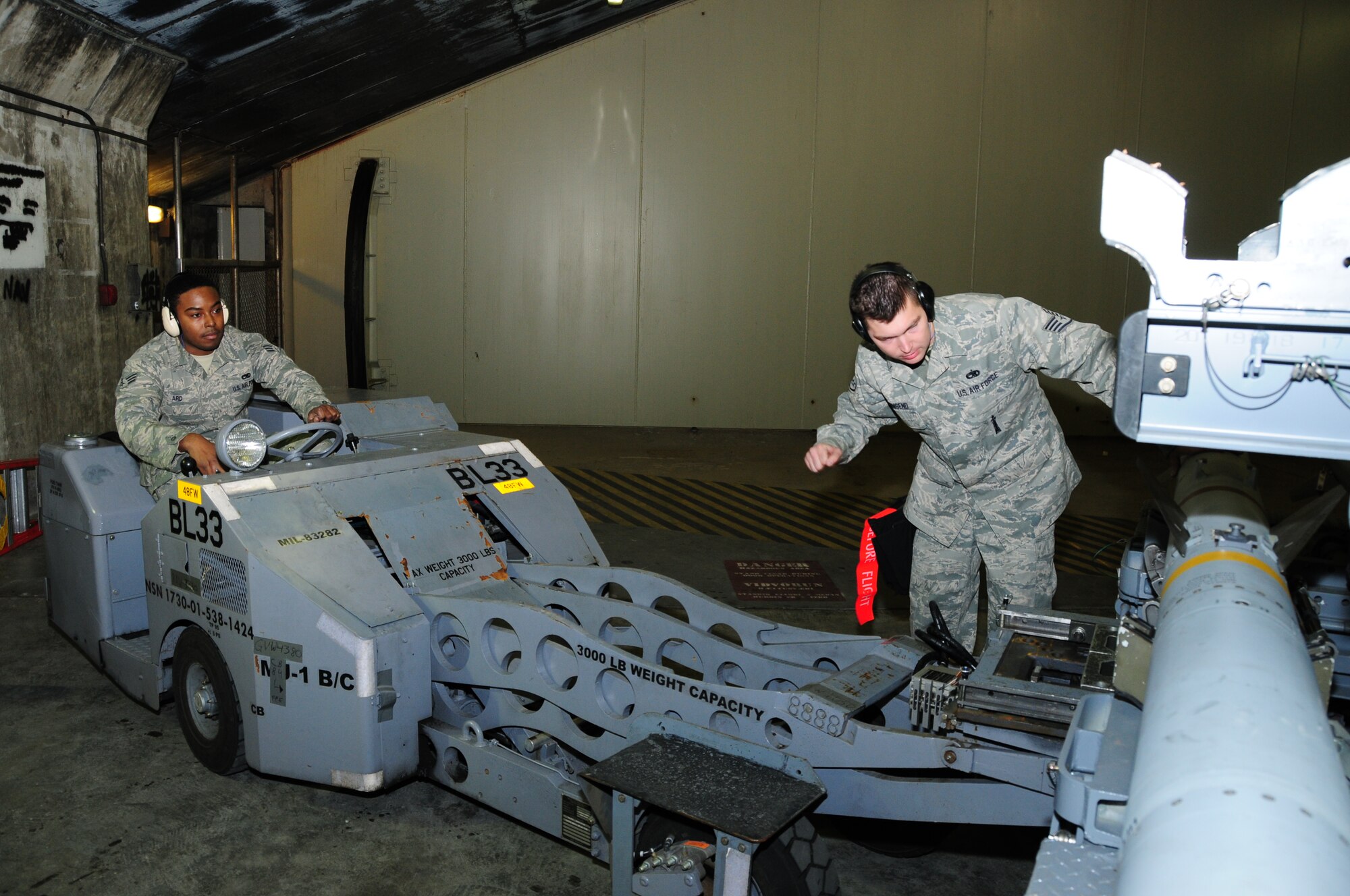 KEFLAVIK, Iceland – Staff Sgt. Ronald Townsend, 493rd Expeditionary Fighter Squadron Weapons Load Crew team chief, guides Senior Airman Jonathan Ard, 493rd EFS Weapons Load Crew team member, as he drives an MJ-1, a vehicle specially made to load munitions, into position to pick up an AIM-120 Advanced Medium-Range Air-to-Air Missile on Sept. 23. (U.S. Air Force photo/Senior Airman Stephen Linch)