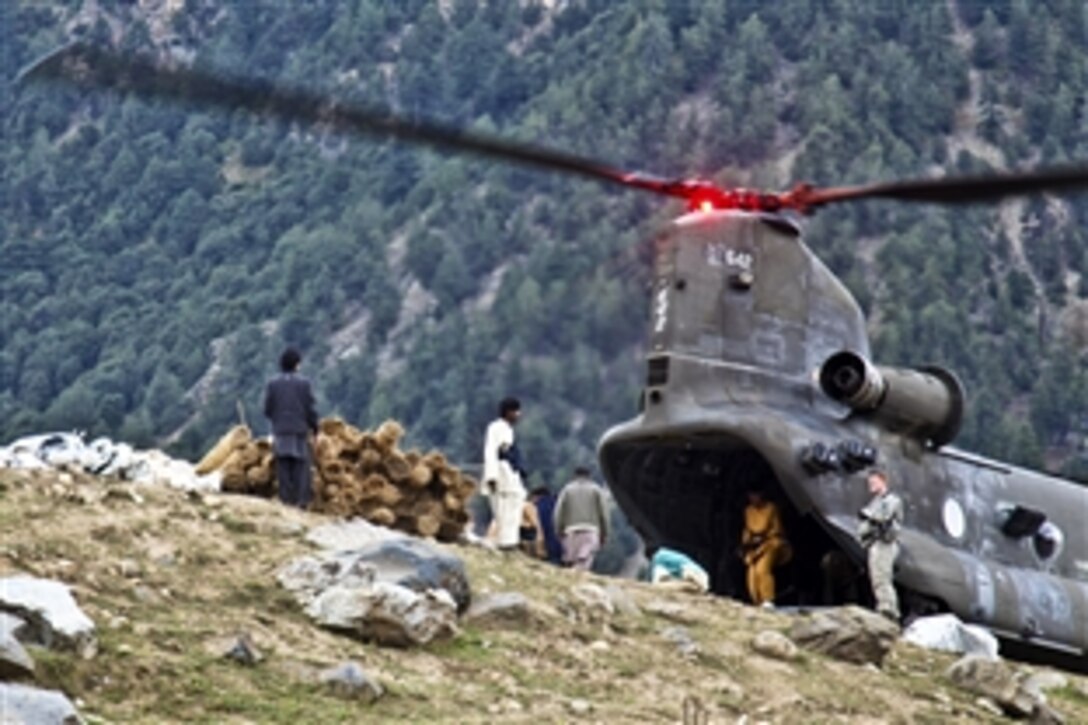 Pakistani men unload construction supplies delivered by a U.S. Army CH-47 Chinook helicopter to rebuild the homes of flood victims in Matlatan, Pakistan, Sept. 28, 2010. The helicopter is from the 16th Combat Aviation Brigade.
