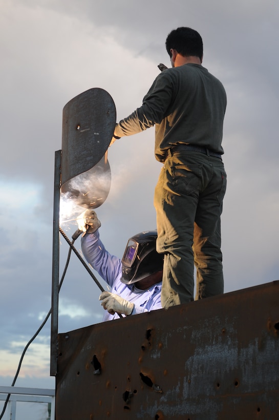 Fernando Godinez, left, TRAX Test Services maintenance crewman, welds the support brace of a fake radar dish on the top of a target shaped like a radar van at the Chocolate Mountain Aerial Gunnery Range, Sept. 29, 2010, as Alex Ribas, TRAX Test Services maintenance crewman, supports the dish. A five-man team traveled the remote areas of the range inspecting and repairing the hundreds of targets in anticipation of the beginning of the Weapons and Tactics Instructor course. TRAX and the station’s Range Maintenance section construct and repair more than 300 targets to provide aviators with a realistic training environment before each WTI.