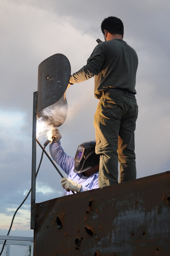 Fernando Godinez, left, TRAX Test Services maintenance crewman, welds the support brace of a fake radar dish on the top of a target shaped like a radar van at the Chocolate Mountain Aerial Gunnery Range, Sept. 29, 2010, as Alex Ribas, TRAX Test Services maintenance crewman, supports the dish. A five-man team traveled the remote areas of the range inspecting and repairing the hundreds of targets in anticipation of the beginning of the Weapons and Tactics Instructor course. TRAX and the station’s Range Maintenance section construct and repair more than 300 targets to provide aviators with a realistic training environment before each WTI.