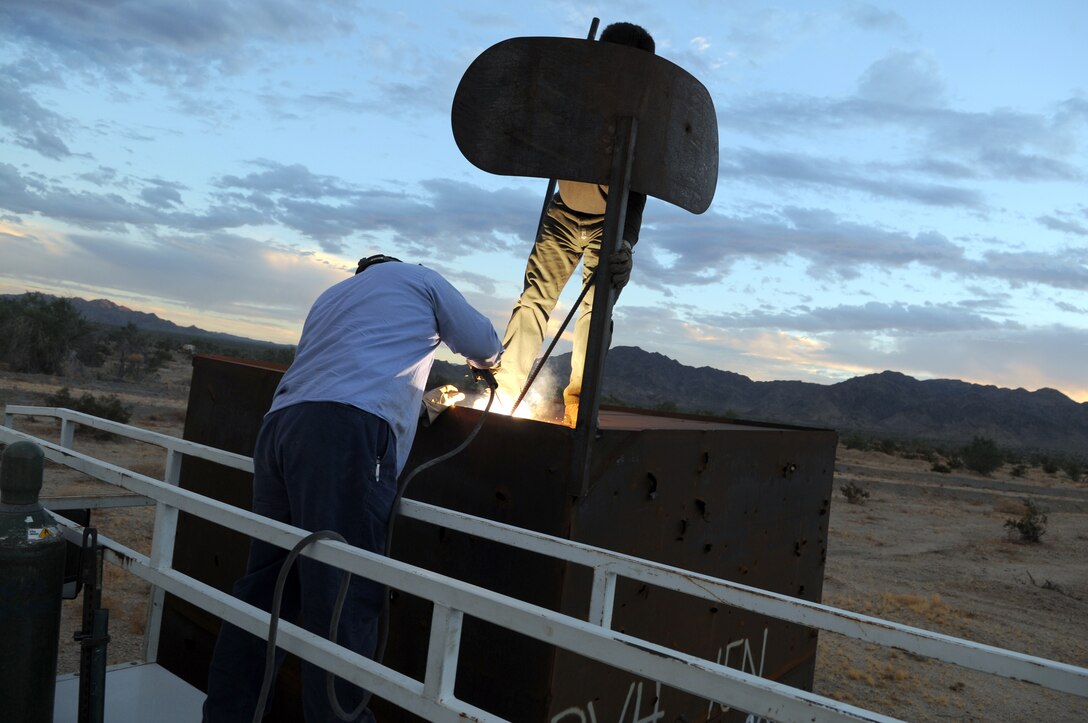 Fernando Godinez, left, TRAX Test Services maintenance crewman, welds the support brace of a fake radar dish on the top of a target shaped like a radar van at the Chocolate Mountain Aerial Gunnery Range, Sept. 29, 2010, as Alex Ribas, TRAX Test Services maintenance crewman, supports the dish. A five-man team traveled the remote areas of the range inspecting and repairing the hundreds of targets in anticipation of the beginning of the Weapons and Tactics Instructor course. TRAX and the station’s Range Maintenance section construct and repair more than 300 targets to provide aviators with a realistic training environment before each WTI.