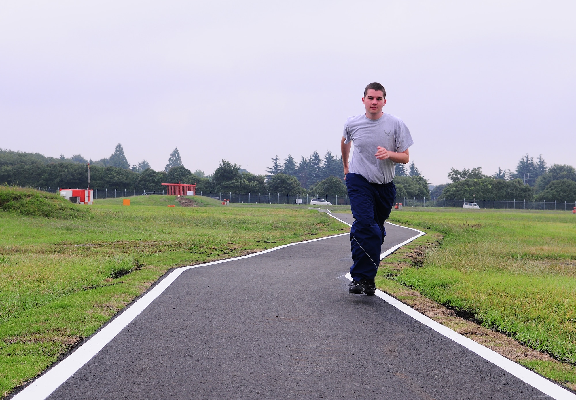YOKOTA AIR BASE, Japan - Airman 1st Class Ryan Lis, 374th Airlift Wing Public Affairs broadcaster, runs down the newly opened bike and jogging path that allows bicycle and pedestrian traffic to cross this end of the base without entering the South overrun.  Earphone use is authorized on the enclosed portion of the path, but not on any roadway. Pedestrians are not authorized on the roadway and must not leave the path. (U.S. Air Force photo/Staff Sgt. Stacy Moless)