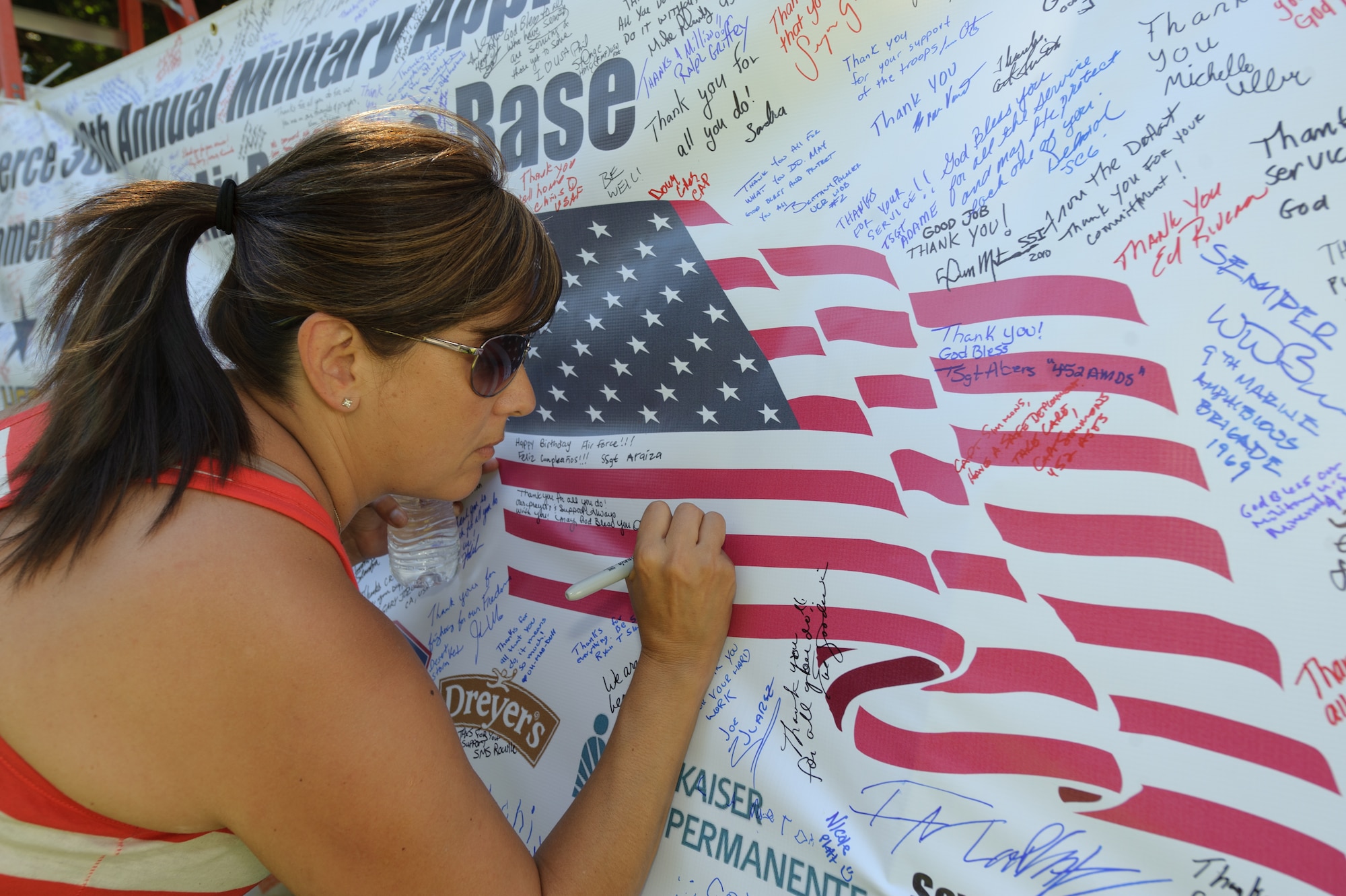 A young woman show her support for the men and women of the base by writing a message on the thank you banner during the 38th Annual Military Appreciation Picnic at March Air Reserve Base, Calif., Sept. 18. (U.S. Air Force photo by Staff Sgt. Matthew Smith)