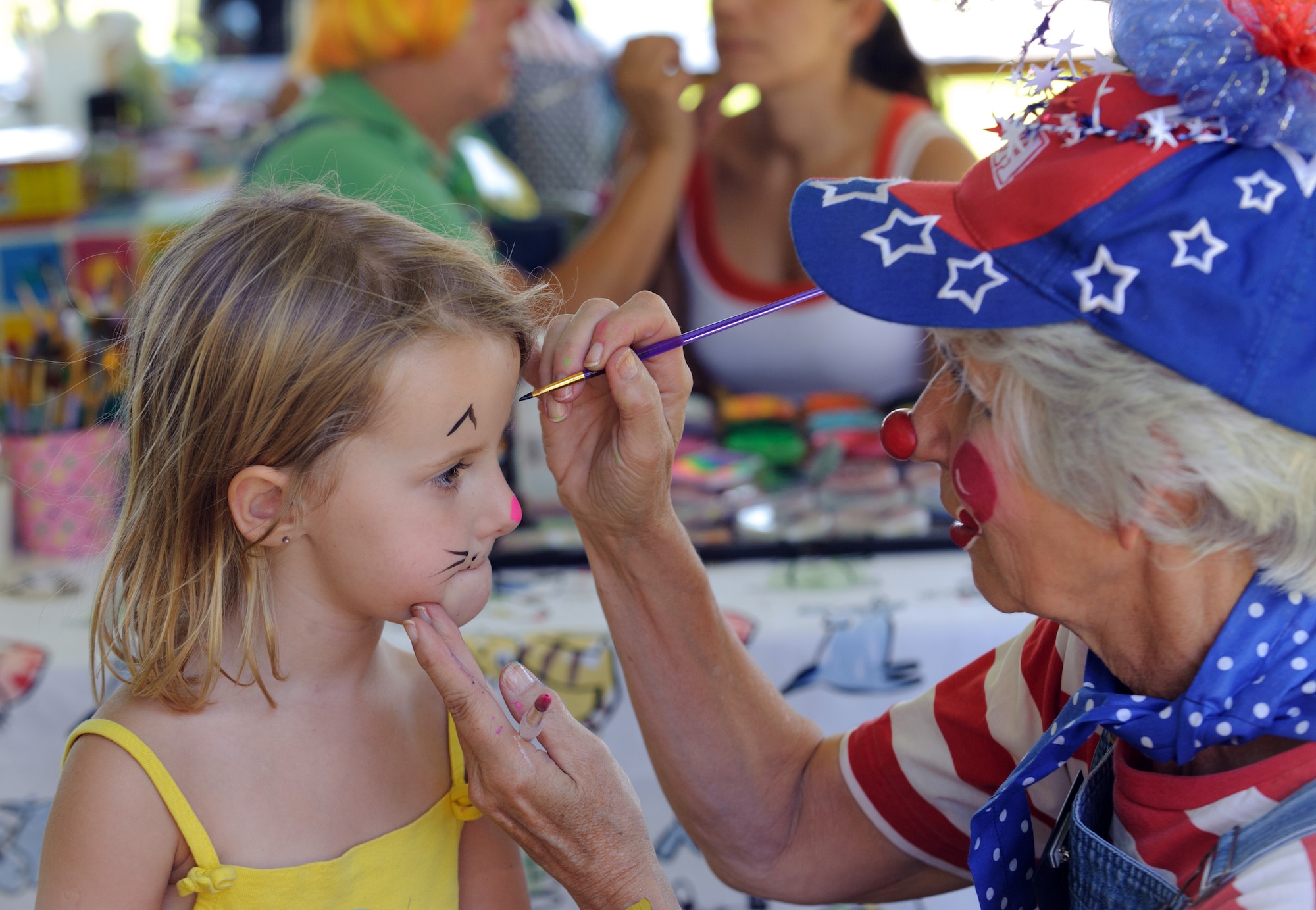 A volunteer from Happy Clowns of Hemet paints the face of four-year-old Natalia, daughter of a 729th Airlift Squadron officer, during the 38th Annual Military Appreciation Picnic at March Air Reserve Base, Calif., Sept. 18. (U.S. Air Force photo by Staff Sgt. Matthew Smith)