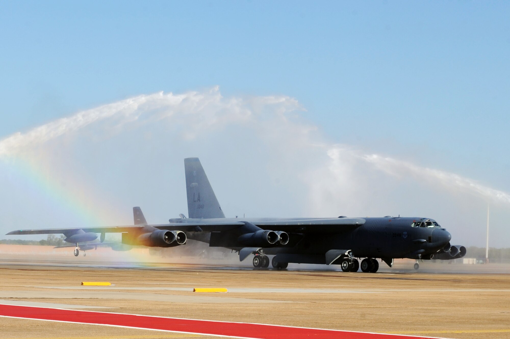 BARKSDALE AIR FORCE BASE, La. -- Col. Gregory Smith, 2nd Operations Group commander, maneuvers his B-52H Stratofortress through the water spraying from fire trucks after his "fini" flight Sept. 29.  It's traditional for fire trucks to join the crowd in welcoming the pilot back from his final flight with a spray down. (U.S. Air Force photo/Senior Airman Brittany Y. Bateman)(RELEASED)