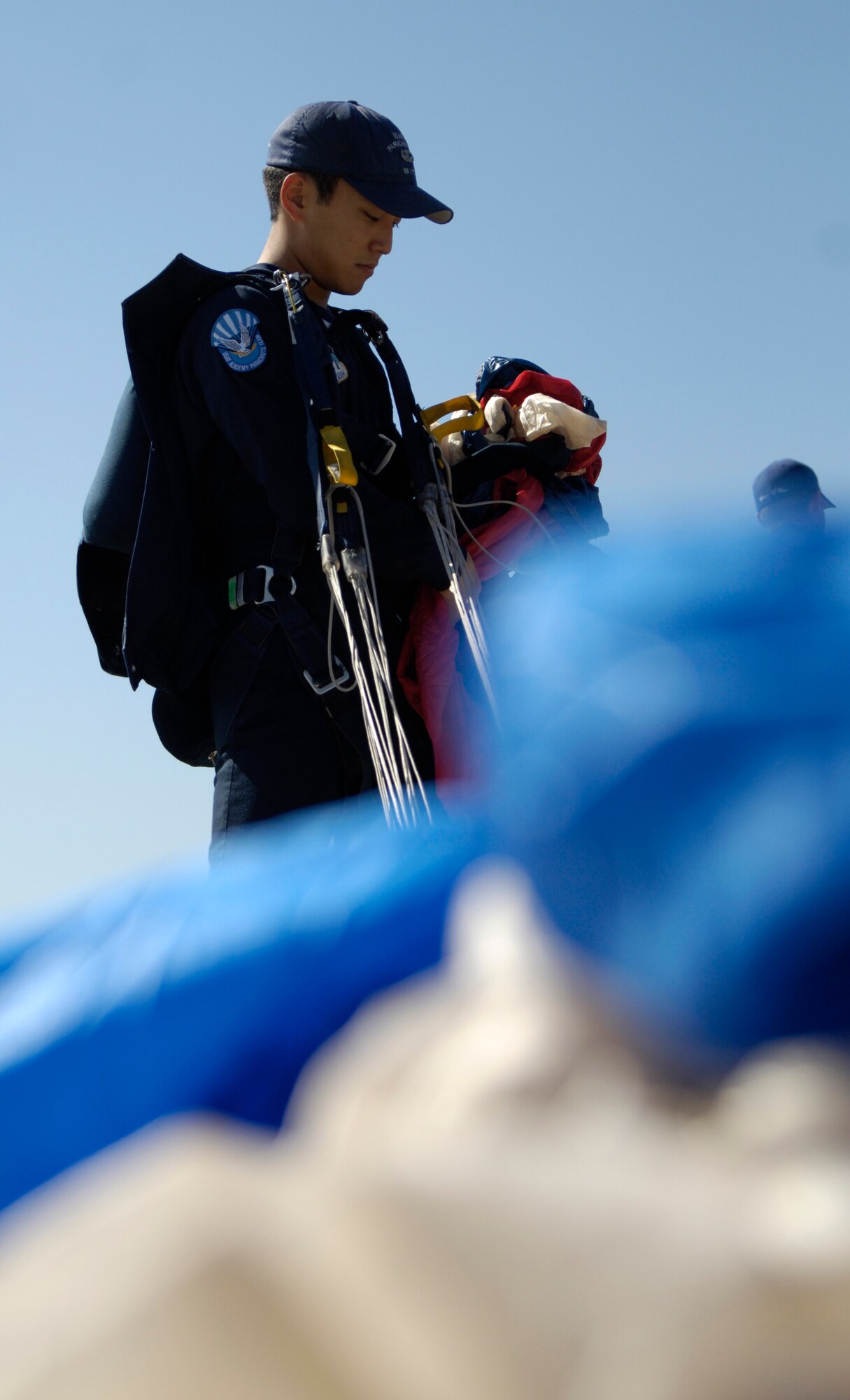 Cadet 1st Class Alexander Choi, U.S. Air Force Academy Wings of Blue jumper, folds his parachute after a performance Sept. 25, 2010, McConnell Air Force Base, Kan. Cadet Choi was one of several acts included in the opening ceremony of McConnell’s 2010 Open House and Air Show. More than 95,000 guests joined McConnell to experience military life. (U.S. Air Force photo/Airman 1st Class Armando A. Schwier-Morales)