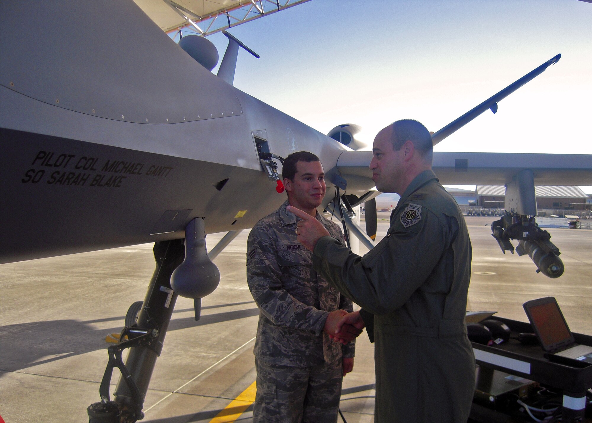 Col. Michael Gantt, 53rd Wing commander, shakes hands with Senior Airman Mario Munive, 432nd Aircraft Maintenance Squadron, in front of the 53rd's flagship MQ-9 Remotely Piloted Aircraft.  Colonel Gantt flew the MQ-9 for an orientation flight during his visit to his squadron, the 556th Test And Evaluation Squadron at Creech Air Force Base, Nevada.  (Courtesy photo.)