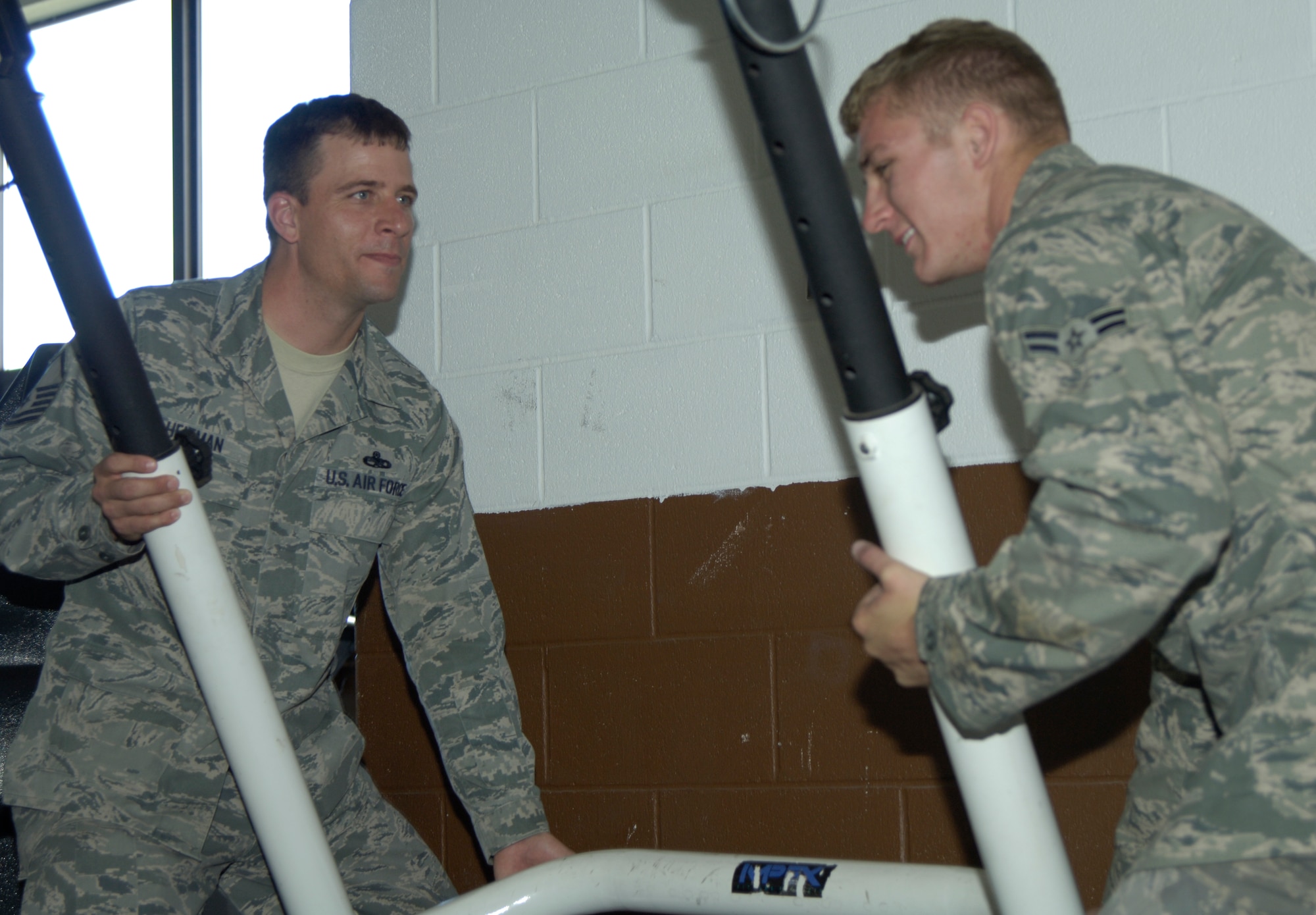(Left) Master Sgt. Jeremy S. Heitman, 22nd Aircraft Maintenance Squadron flying crew chief and security manager, moves gym equipment with the help of Airman 1st Class Scotty Carte, 22nd AMXS assistant flying crew chief, Sept. 28, 2010, McConnell Air Force Base, Kan. Sergeant Heitman is in charge of additional duties, one of which is the rearrangement of the flightline gym. The Sacramento, Calif., native is also in charge of 22nd AMXS temporary duty assignments.  