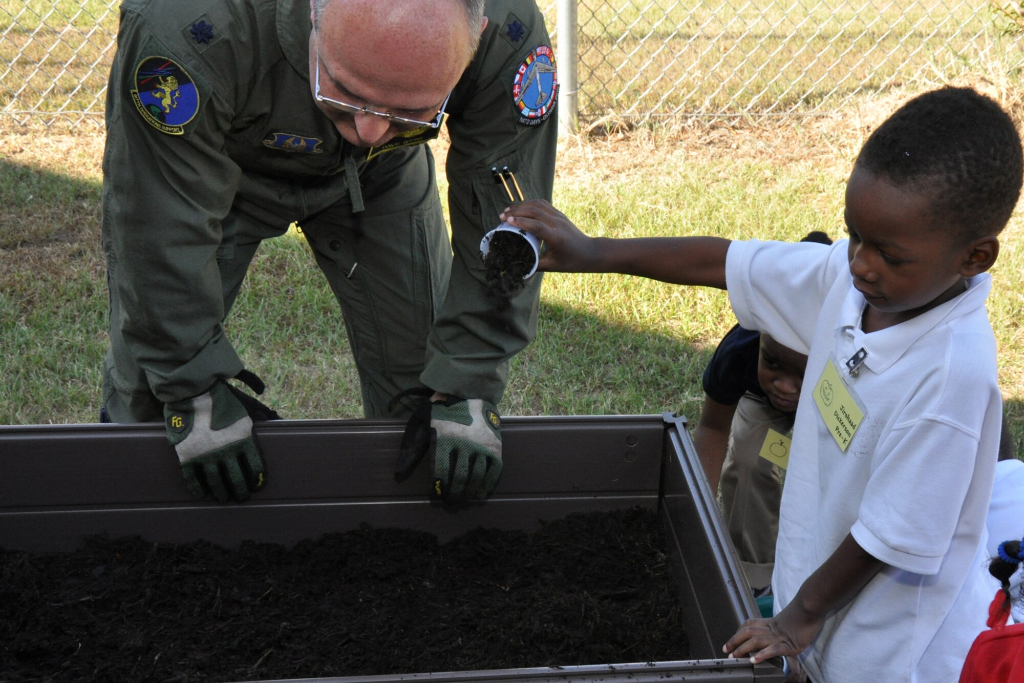 Lt. Col. David Webb, commander of the 917th Operations Support Flight, at Barksdale Air Force Base, La., gets a little assistance from Jirshaad Dickerson in filling up a portable flower bed installed at Westwood Elementary School in Shreveport, La., Sept. 28, 2010. Jirshaad is a Pre-K student at Westwood. Westwood Pre-K teacher, Mrs. Valli Webb planned the planting project to allow her students the opportunity to see the growth of their efforts. Through the year, plans are to replace the flowers with seasonal plants and vegetables to be a continuing lesson for the students that could last a lifetime. Westwood Elementary supports children from Pre-K through 5th Grade. (U.S. Air Force photo/Tech. Sgt. Jeff Walston)