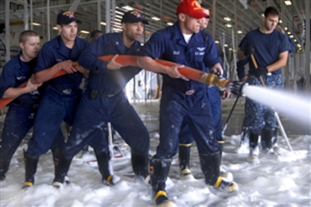 U.S. Navy sailors wash down the deck after a foam-systems check on the USS Makin Island in the Pacific Ocean, Sept. 29, 2010. 