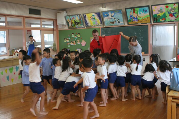 Cpl. Marcie McWaters, Marine Aviation Logistics Squadron 12 community relations coordinator, and 2nd Lt. Richard K. Grainger, volunteer, welcome the stampede of kindergartners during a visit at a local Japanese elementary school Sept. 30. The children were playing a shape association game.
