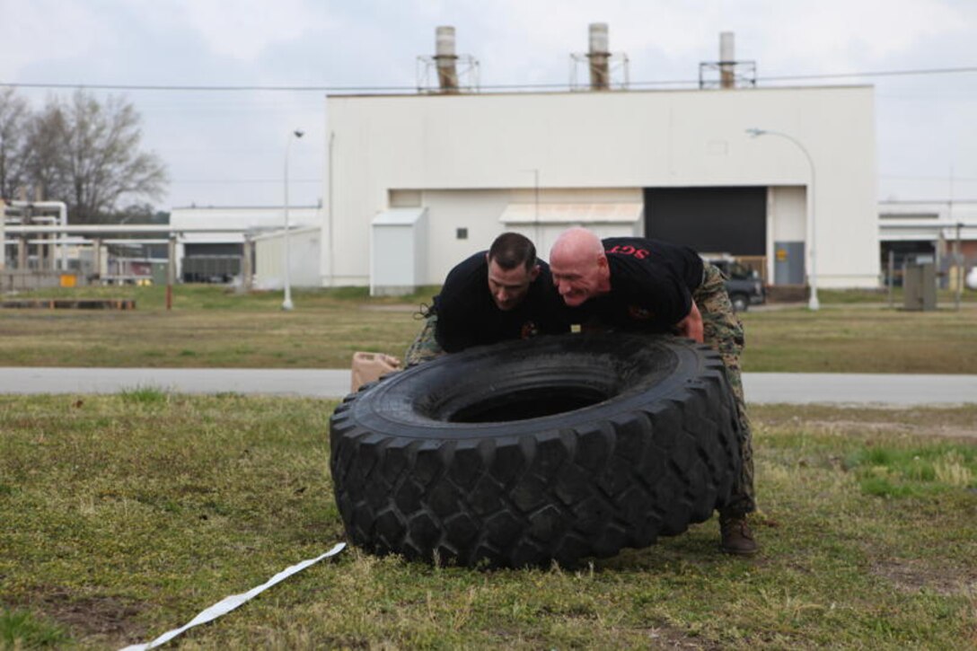 Lt. Col. John Armellino, commanding officer of AITB-East, (left) and Sgt. Major Kenneth Rademacher, the sergeant major for Advanced Infantry Training Battalion, (right) work as a team as they flip a seven-ton’s tire for a set distance during the Tough Man Competition aboard Camp Geiger, April 1. The Tough Man Competition pitted permanent personnel against each other and was hosted to boost morale and camaraderie.