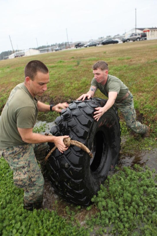 Staff Sgt. Alan Sansovich (left) and Sgt. Kevin Kelley, instructors with the Instructor Training Company, School of Infantry – East, (right) maneuver a seven-ton tire as they try to drag it out of a ditch during the Tough Man Competition aboard Camp Geiger, April 1. The Tough Man Competition pitted permanent personnel against each other and was hosted to boost morale and camaraderie.