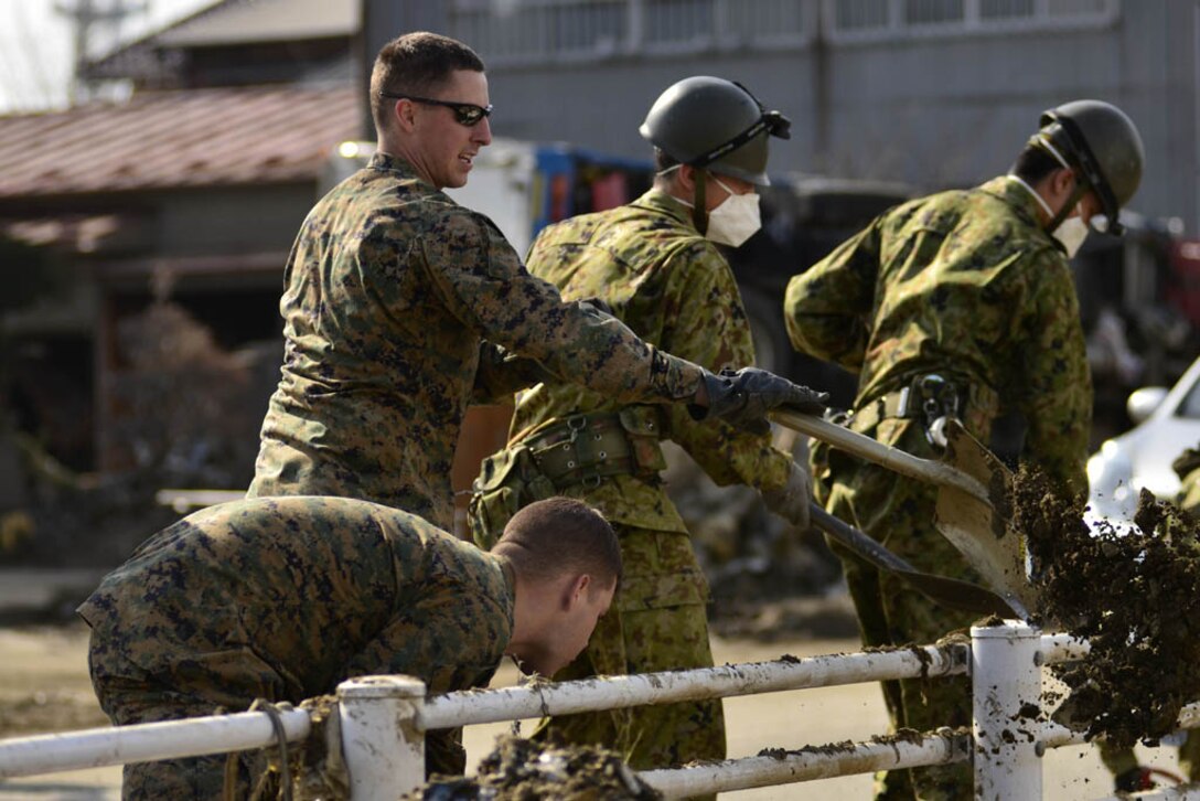 Marines with Combat Logistics Regiment 35, 3rd Marine Logistics Group, III Marine Expeditionary Force, and Joint Task Force Fuji, both Joint Support Forces Japan, work with Japan Ground Self-Defense members to clear the entryway to the schoolyard here April 1. The JGSDF identified the school as particularly hard hit and coordinated a bilateral cleanup that involved Marines, sailors, soldiers and airmen working alongside JGSDF members.